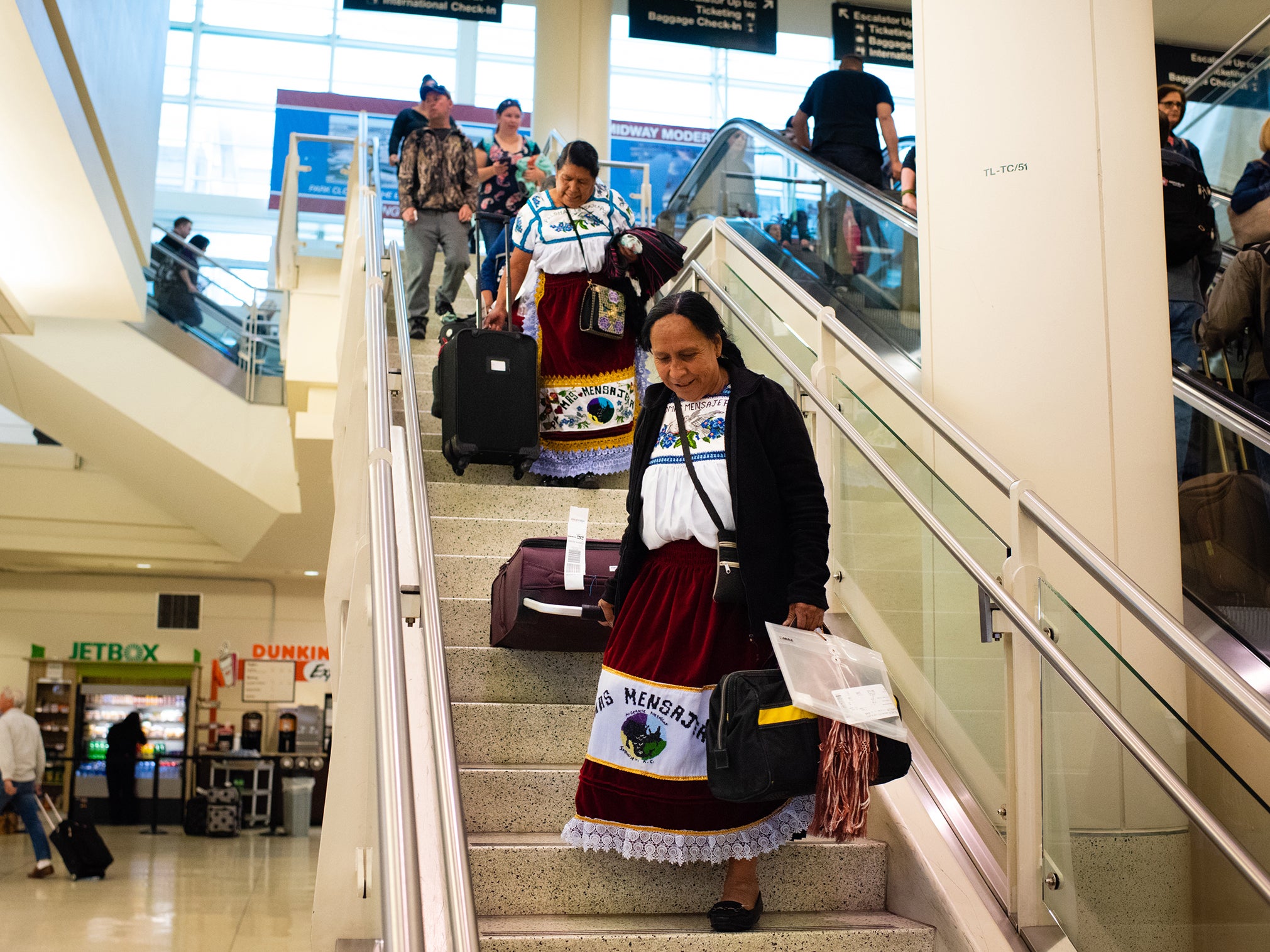 Maria Leonarda Pineda Joaquin, 68, drags her suitcases down the stairs at the airport in Chicago because she is afraid of the nearby escalators