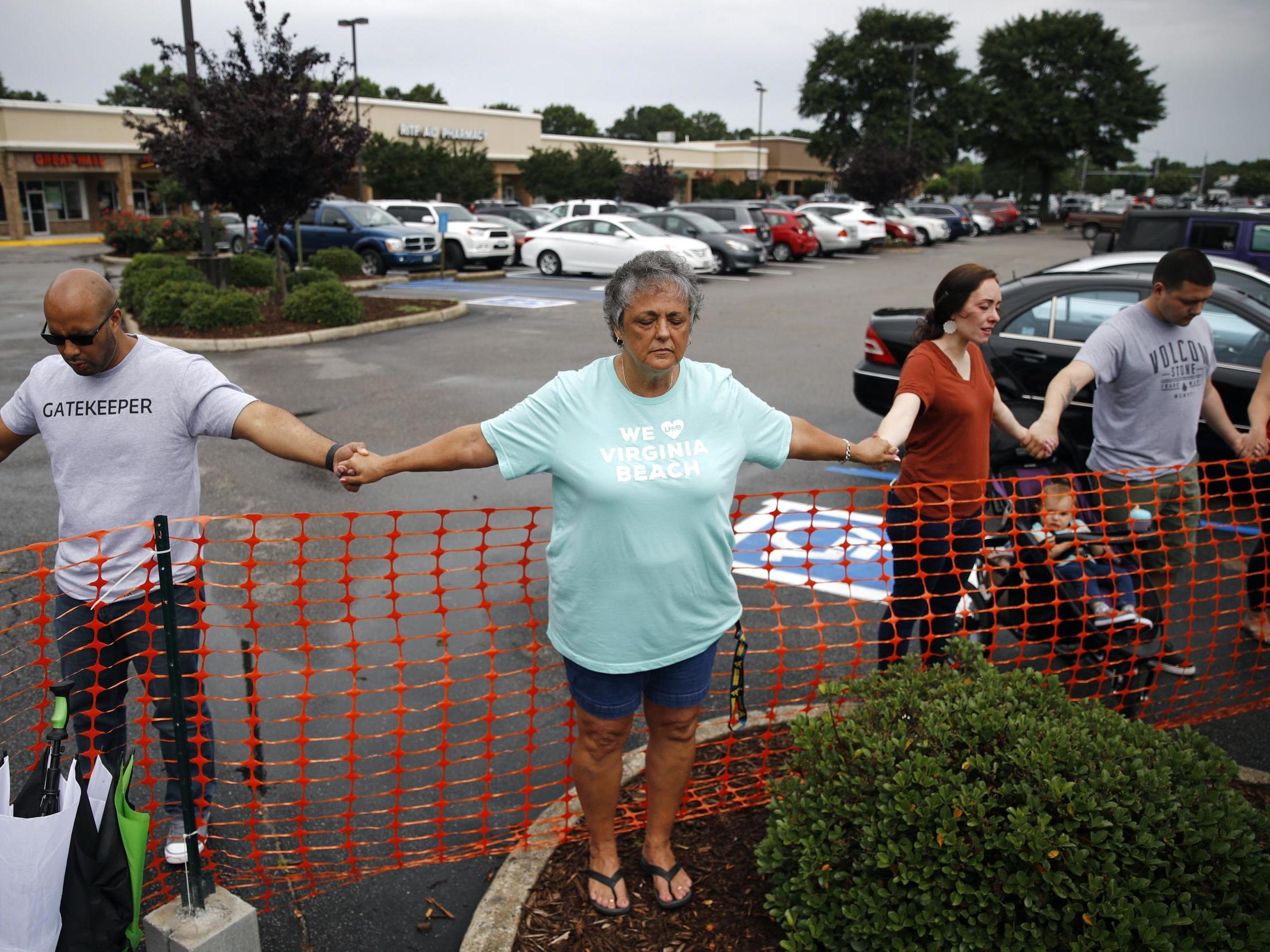 Lisa Dunaway, centre, of Virginia Beach, holds hands with other mourners during a vigil in response to a fatal shooting at a municipal building