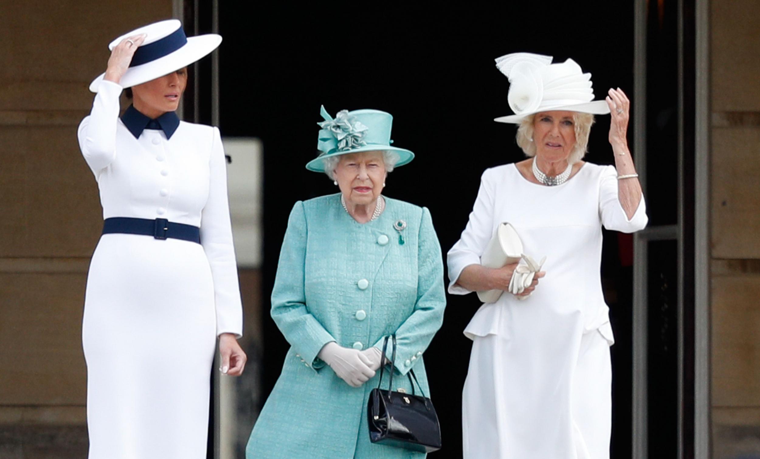 US First Lady Melania Trump (L) and Britain's Camilla, Duchess of Cornwall (R) hold their hats before they are caught by the wind as Britain's Queen Elizabeth II (C) stands with them during a welcome ceremony at Buckingham Palace in central London on June 3, 2019