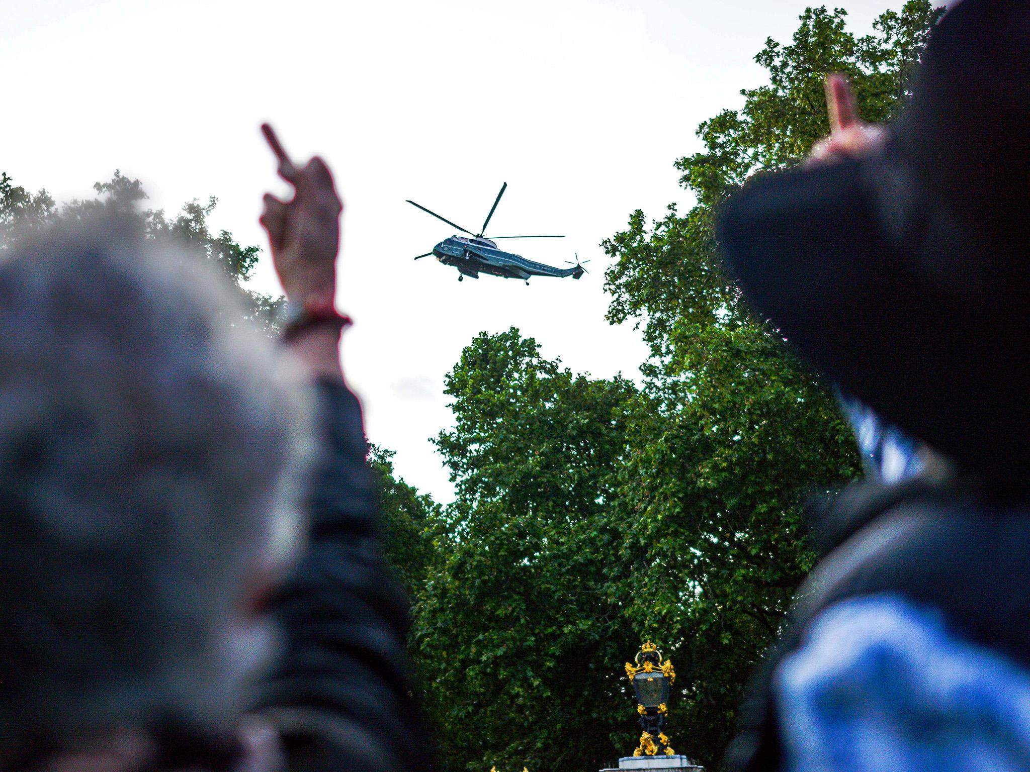 Protesters gesture at the helicopter carrying the president as he arrives at Buckingham Palace on the first day of his visit.