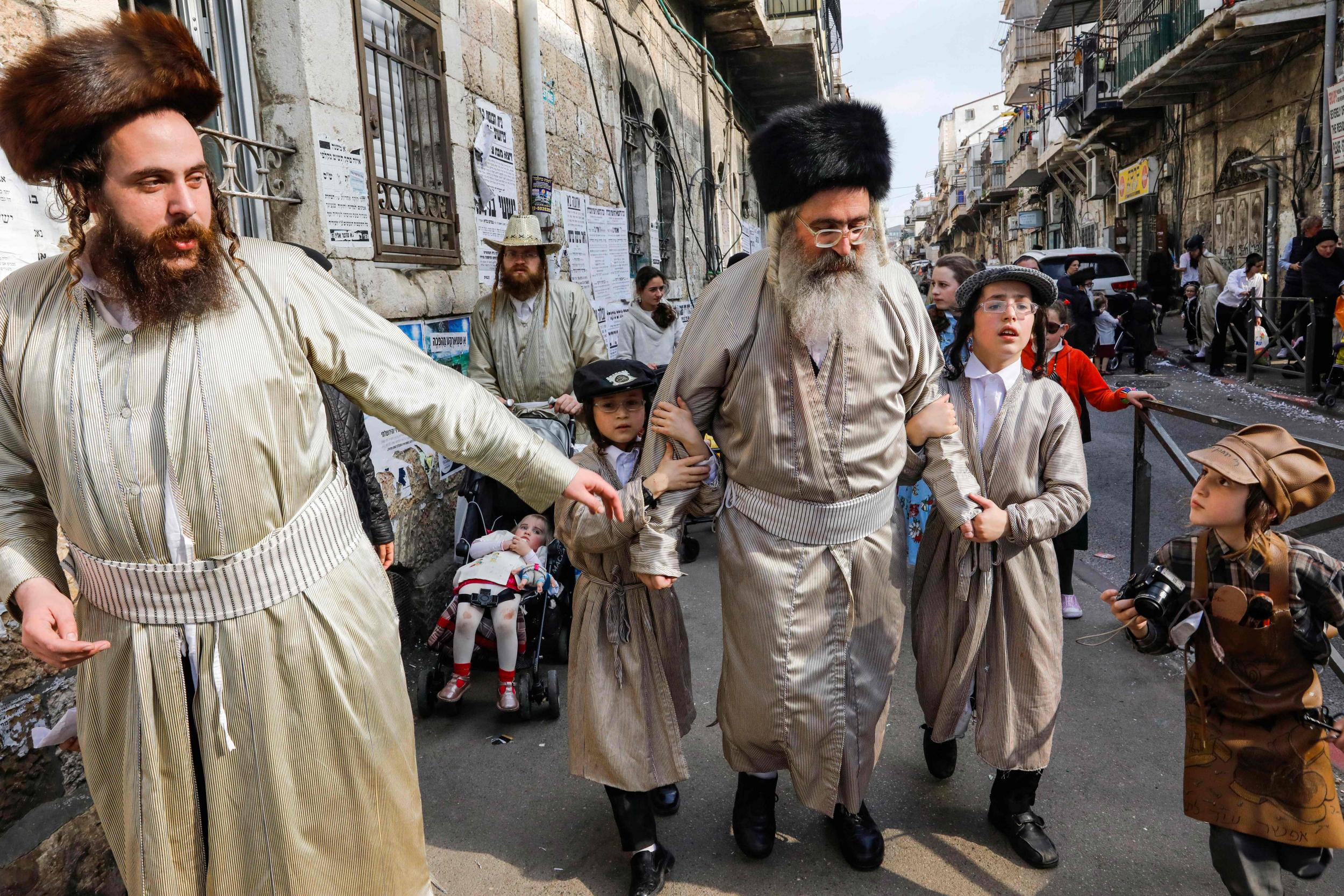 Ultra-Orthodox Jewish men and children wearing Purim costumes dance in the Jerusalem Mea Shaarim neighbourhood in March (AFP/Getty)