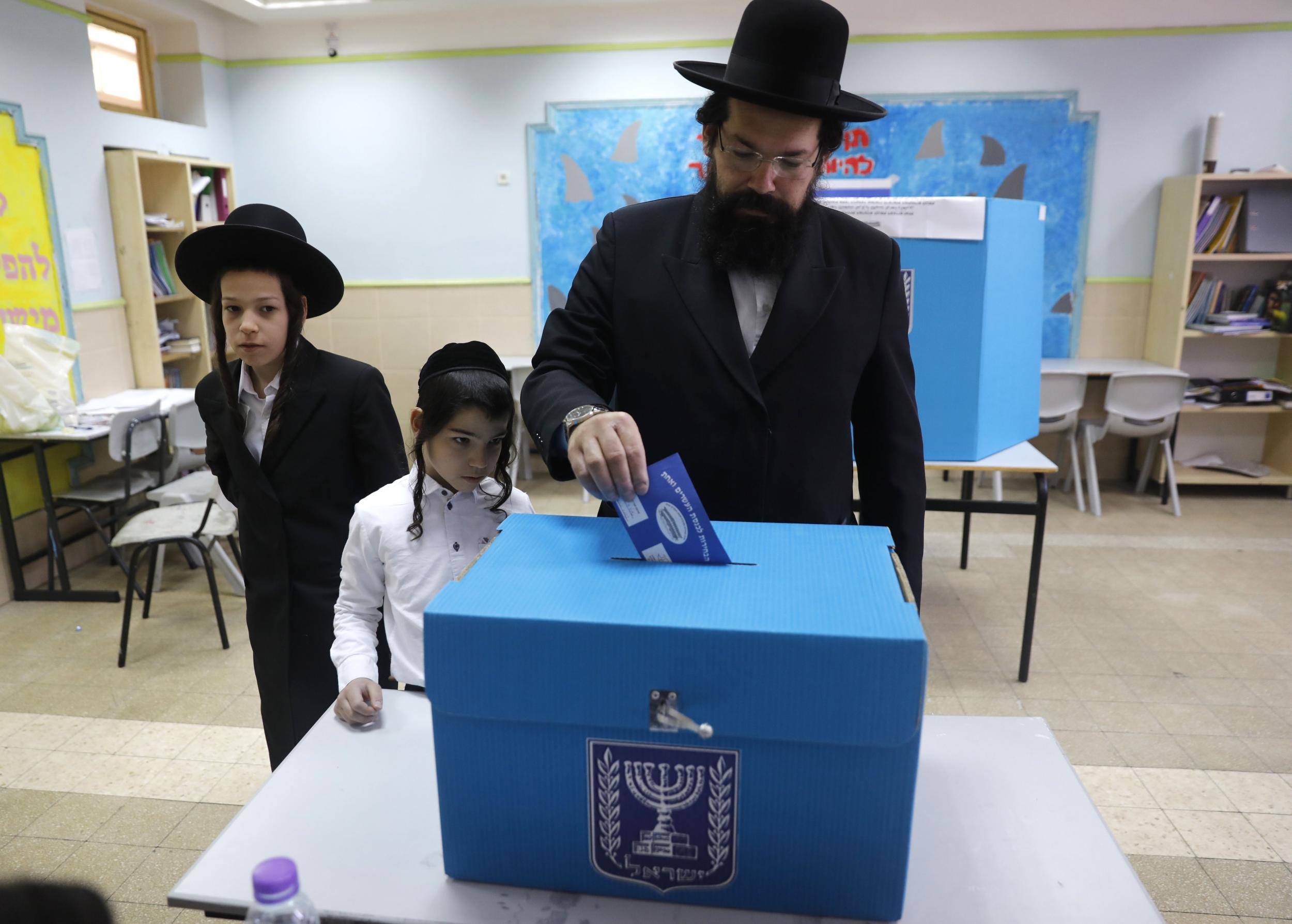 Children watch a Haredi Jewish man cast his vote in Jerusalem during Israel’s parliamentary elections in April