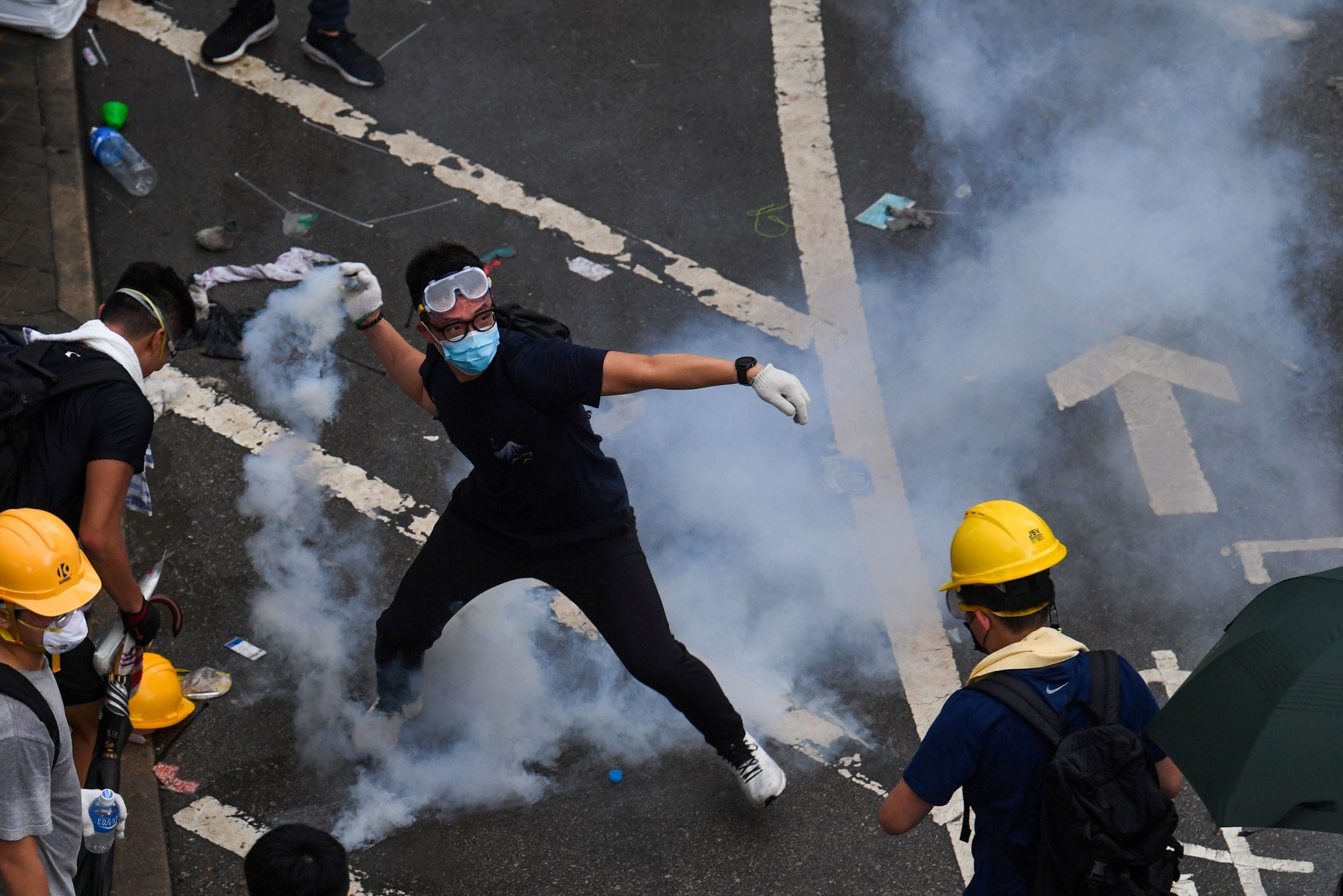 A protester throws back tear gas during clashes with police outside Hong Kong government headquarters on Wednesday