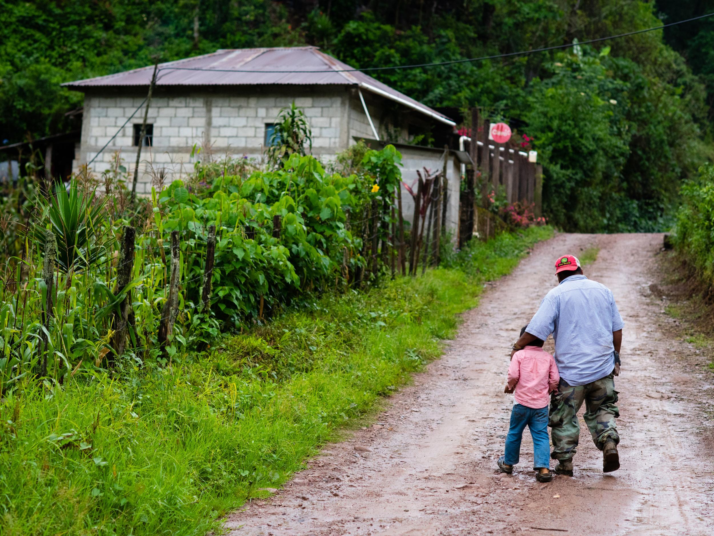 Rodrigo Carrillo and his five-year-old son walk up the dirt road in Hoja Blanca (Sarah L Voisin/Washington Post)