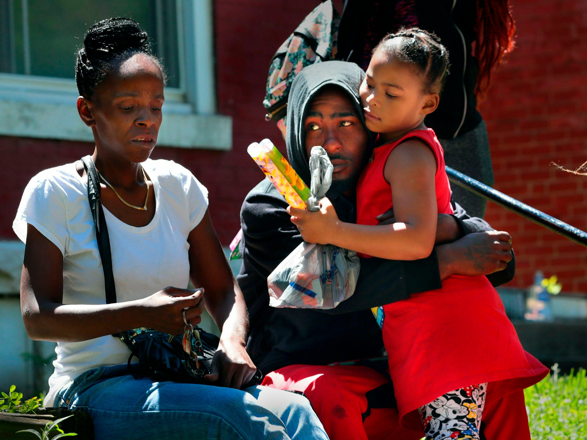 Devation Powell, the father of 3-year-old Kenndei Powell who was shot dead, hugs his cousin Shylar Roberts, 5. Sharonda Edmondson, Kenndei's great-aunt, is sat next to them