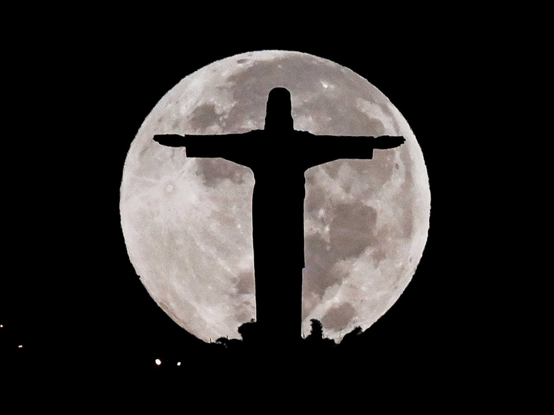 The Cristo Rey monument is silhouetted against the full moon in Cali, Colombia