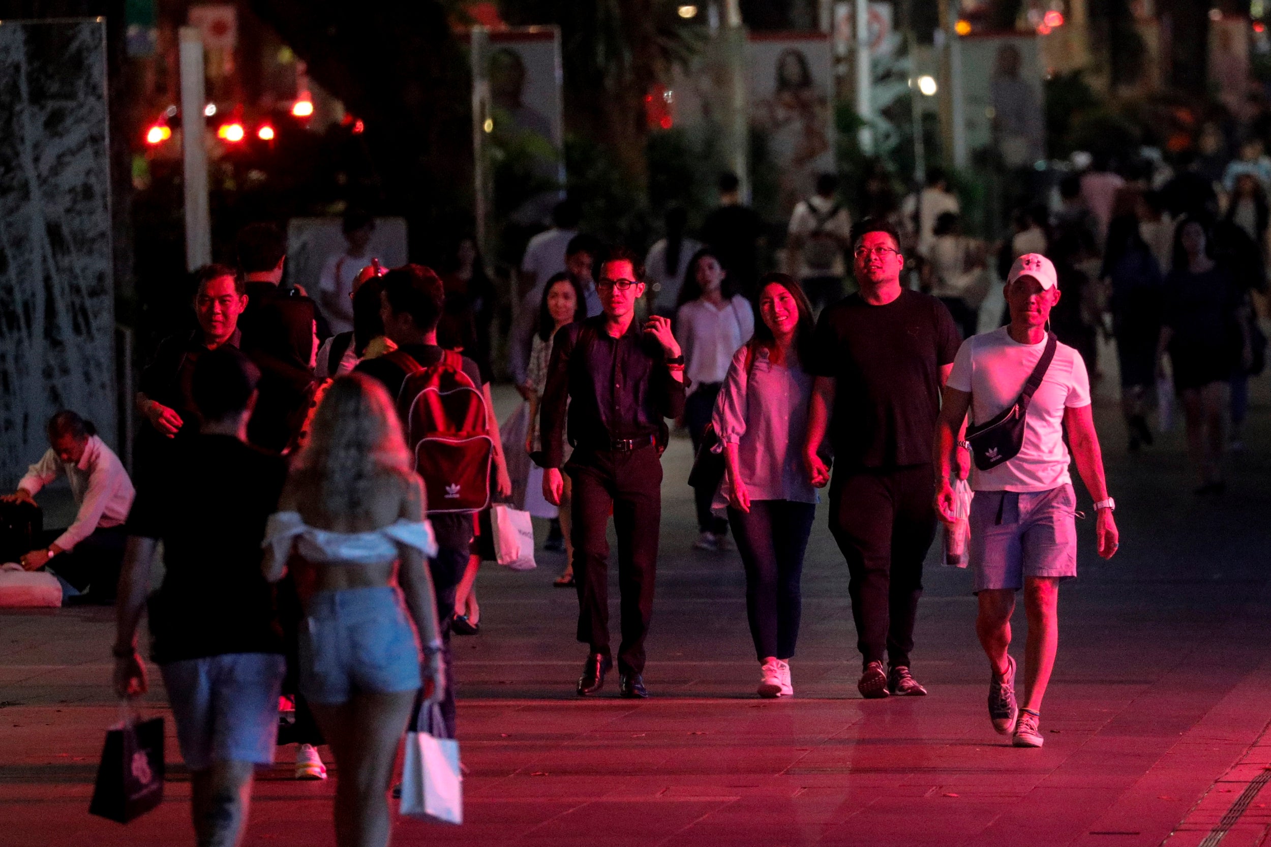 Pedestrians are lit by artificial light from an advertising display screen as they walk along the Orchard Road shopping district in Singapore. Although fundamental to urban infrastructure, artificial lighting is known to affect the natural circadian rhythm of both humans and wildlife
