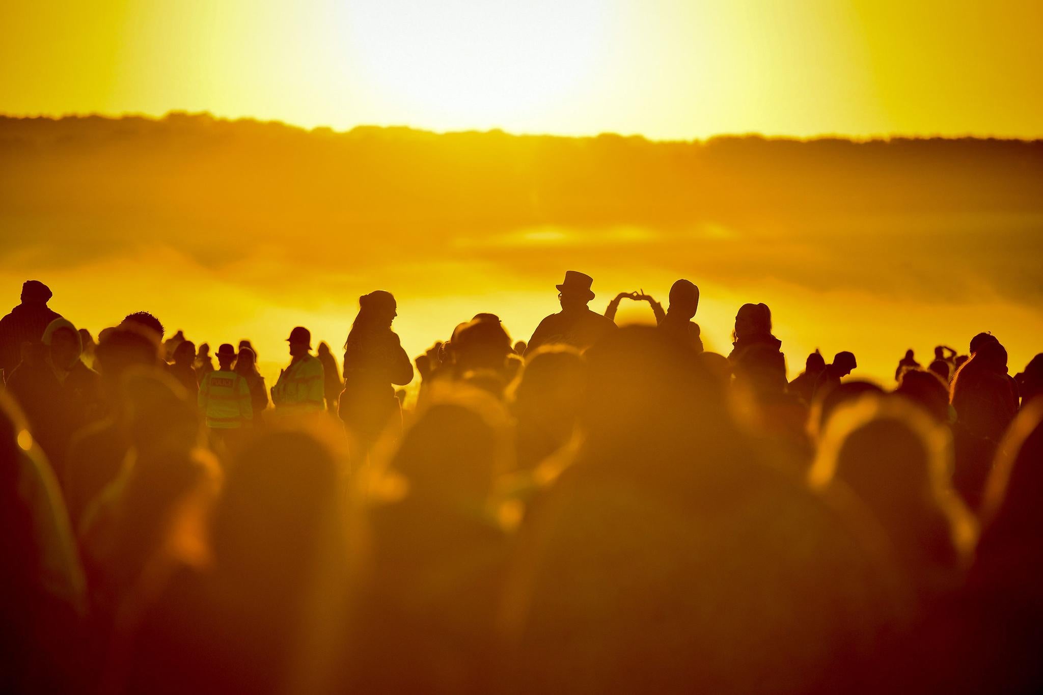 People turn to face the rising sun at Stonehenge at dawn on summer solstice of the longest day of the year at Stonehenge on June 21