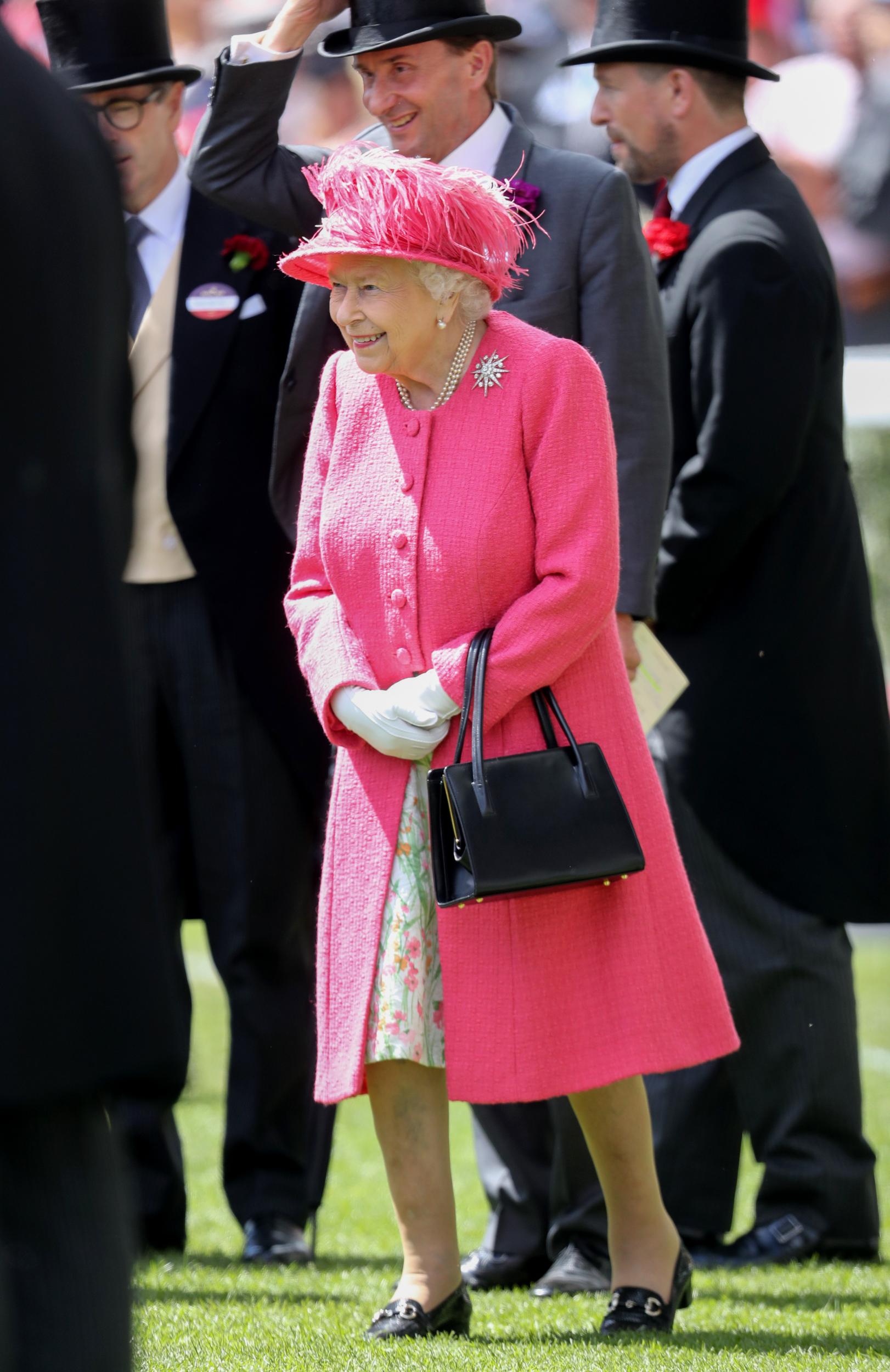 The Queen arrives at Ascot with her customary burst of colour, wearing a rouge, buttoned coat, matching feathered hat and a floral skirt. The monarch accessorises with pearl earrings, a pearl necklace and a star-shaped jewelled brooch.