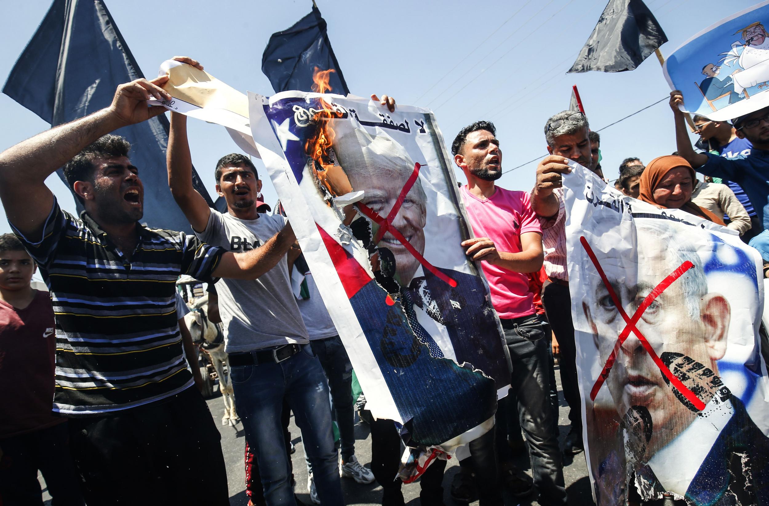 Palestinian demonstrators chant slogans behind defaced posters of Benjamin Netanyahu and Donald Trump during a protest against a US-sponsored Middle East economic conference in Bahrain