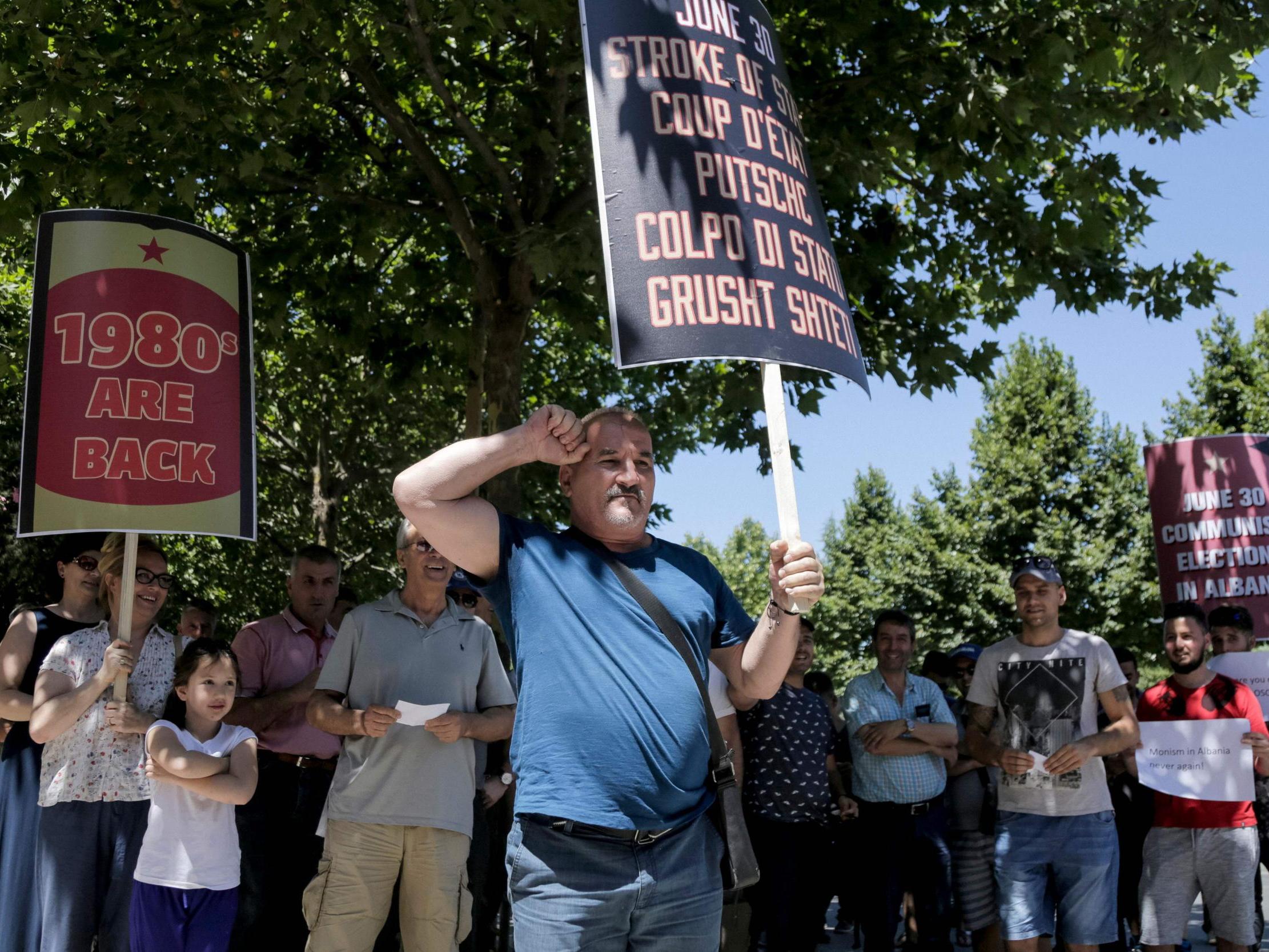 Opposition supporters hold placards reminiscing Albania's dictatorship past as country goes to polls despite opposition boycott