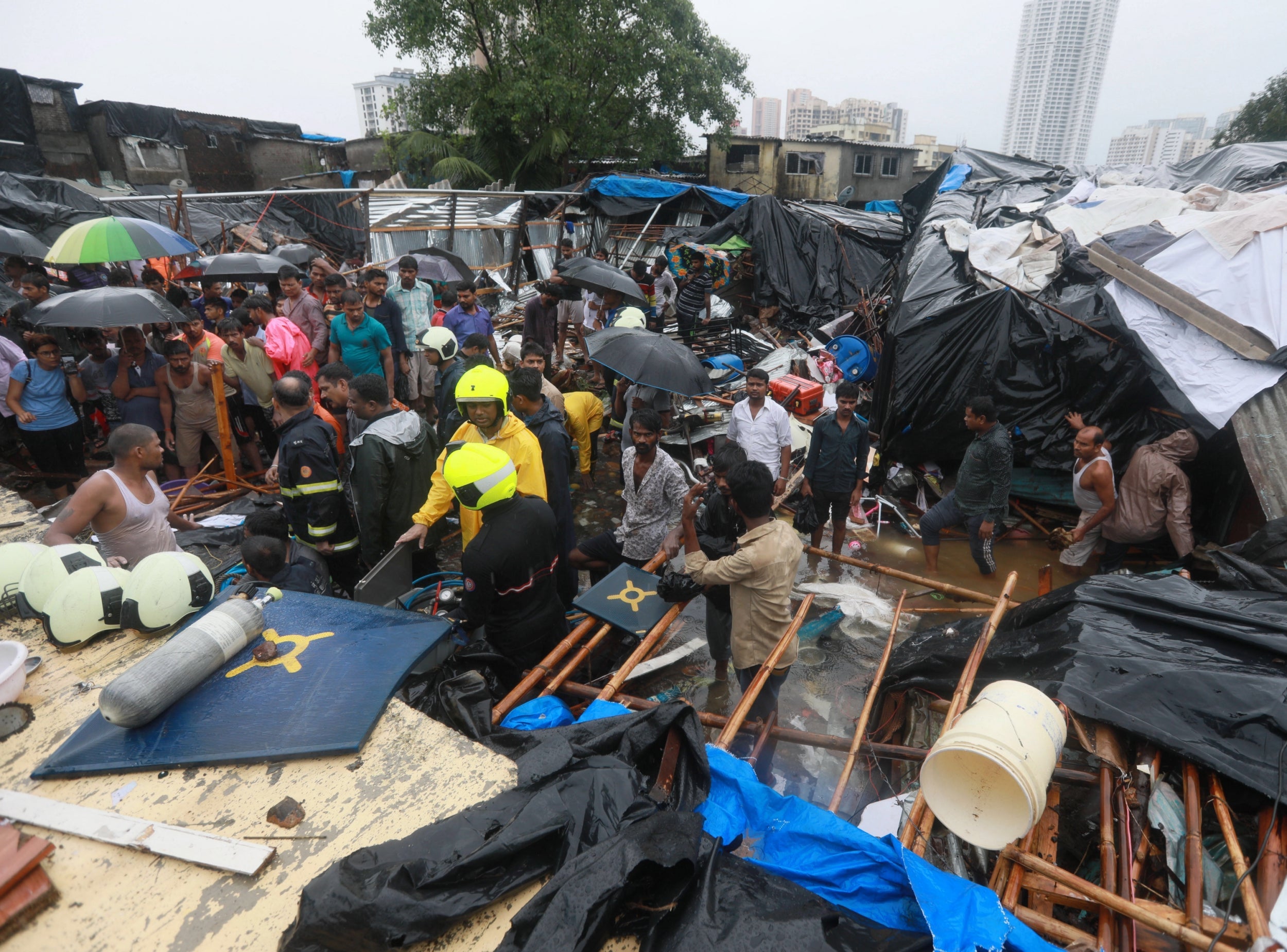 Rescue workers and locals stand near a damaged structure after a wall collapsed at the Pimpri Wada Malad East in Mumbai