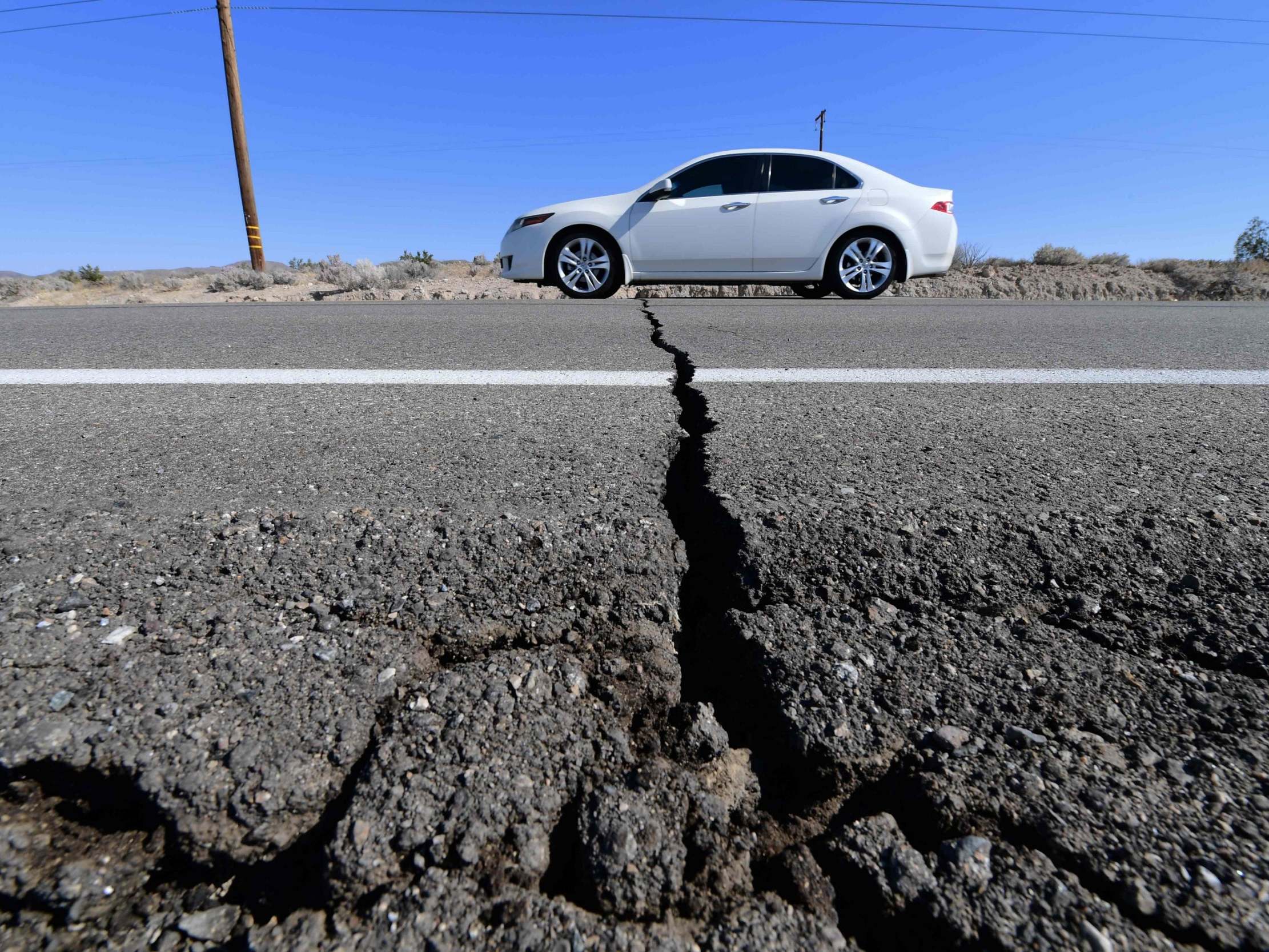 A car drives past a crack in the road on Highway 178, south of Trona, after a 6.4-magnitude earthquake hit in Ridgecrest, California