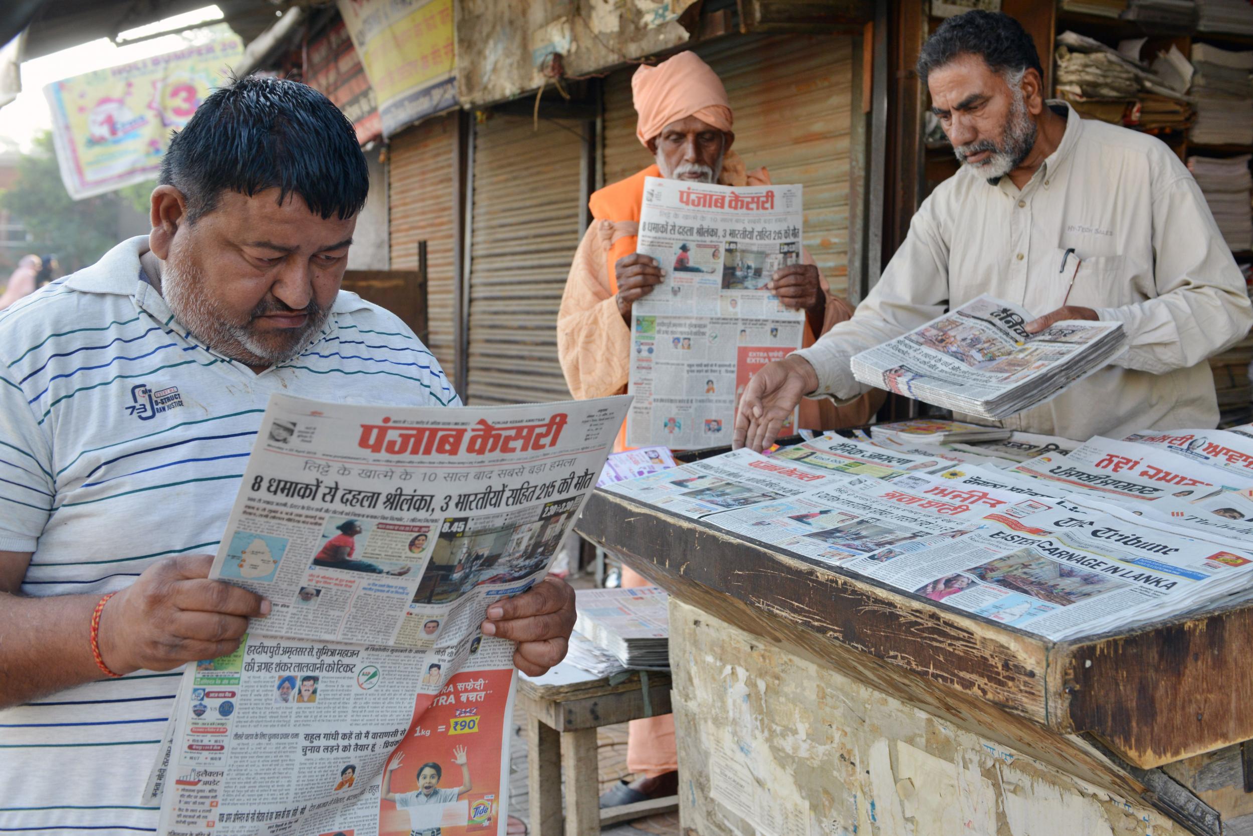 Indian men read newspapers displaying front page news on the Easter Sunday bombings in Sri Lanka (Getty)