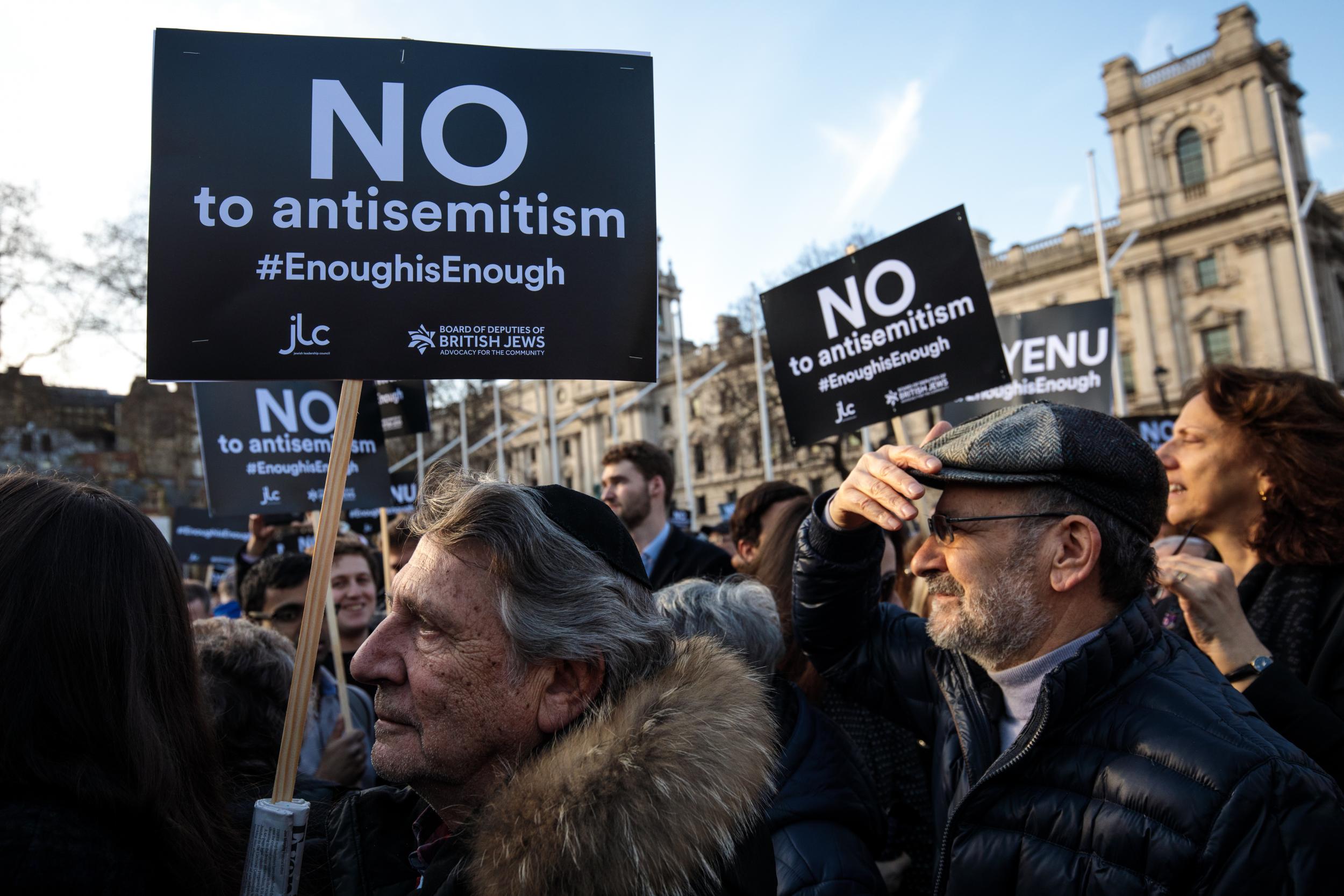 Protesters hold placards as they demonstrate in Parliament Square, London, against antisemitism.