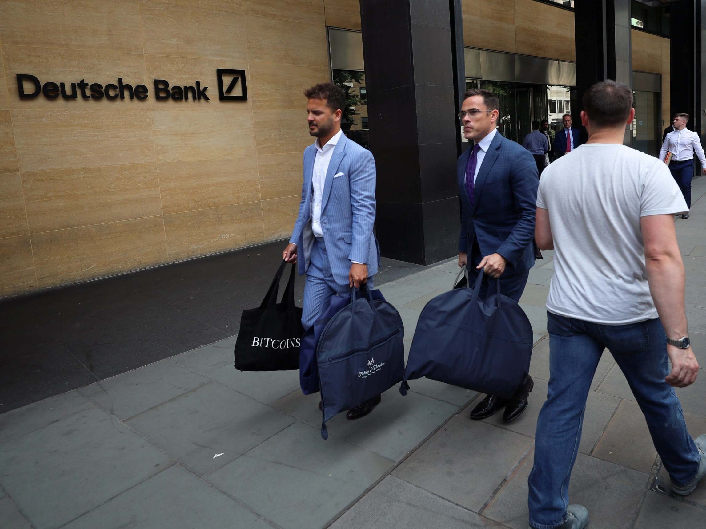 Tailors carrying suit bags leave Deutsche Bank office in London