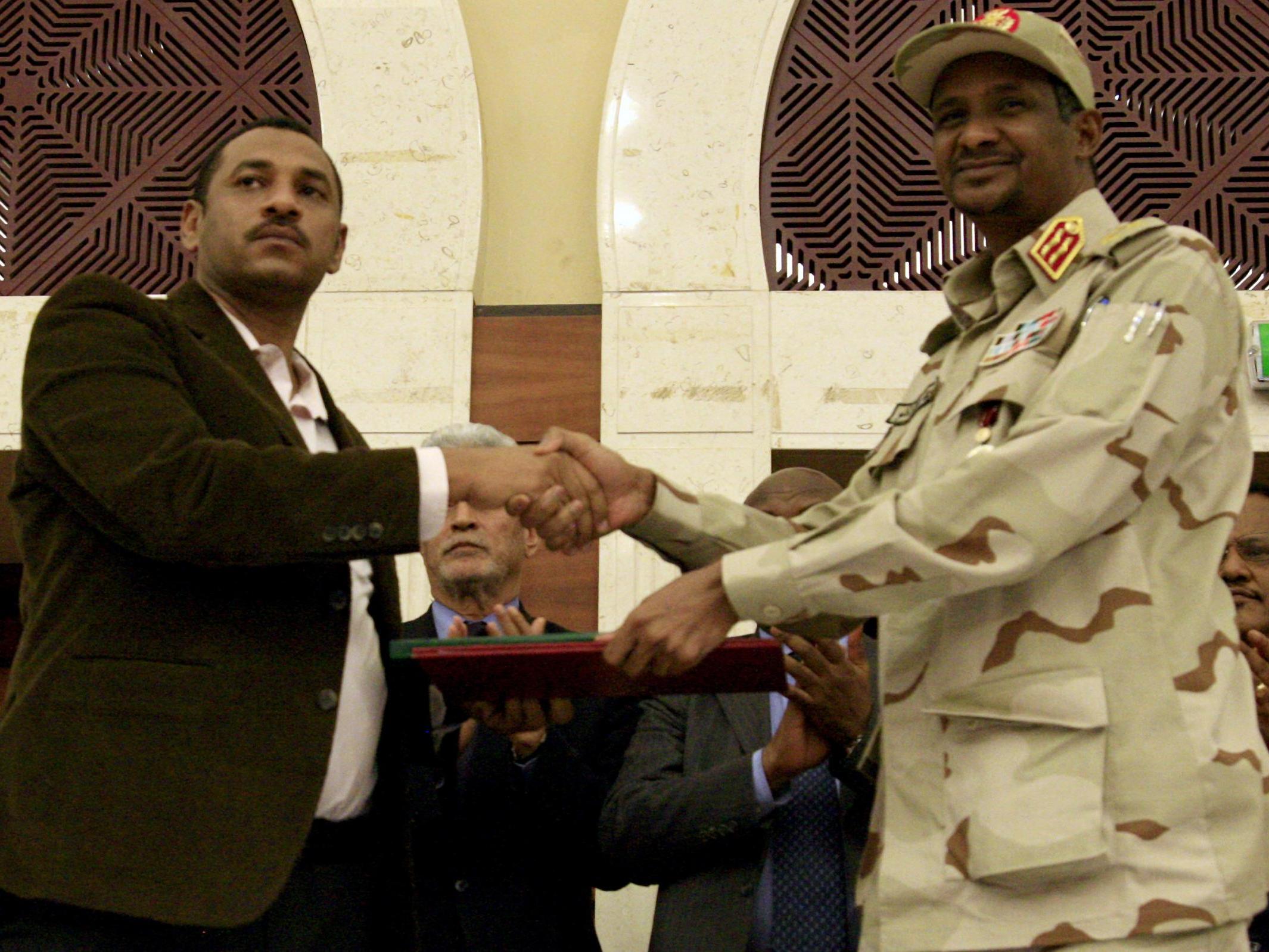 Sudanese deputy chief of the ruling military council and protest movement leader shake hands after inking an agreement