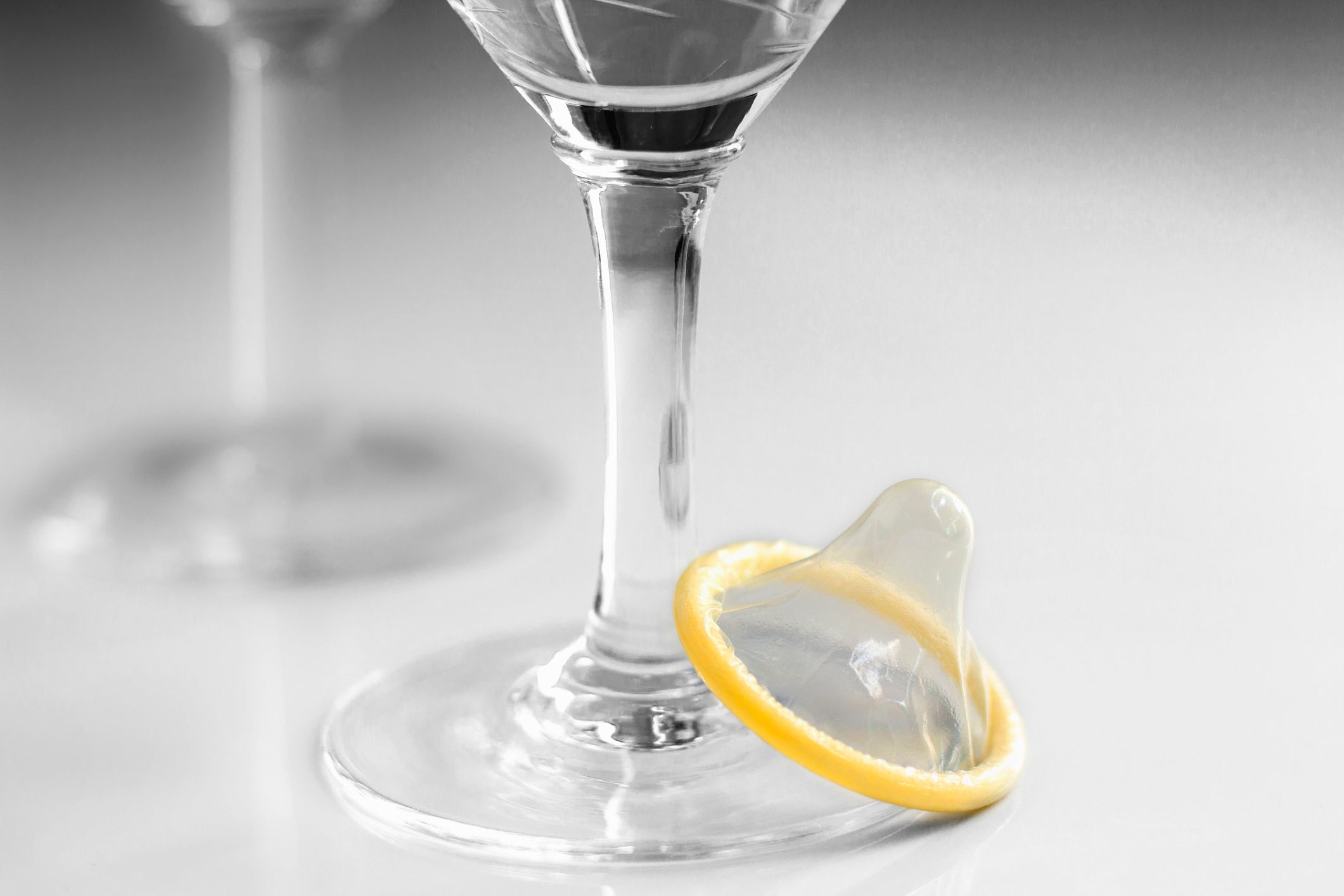 Condom with a glasses of liquor on white background