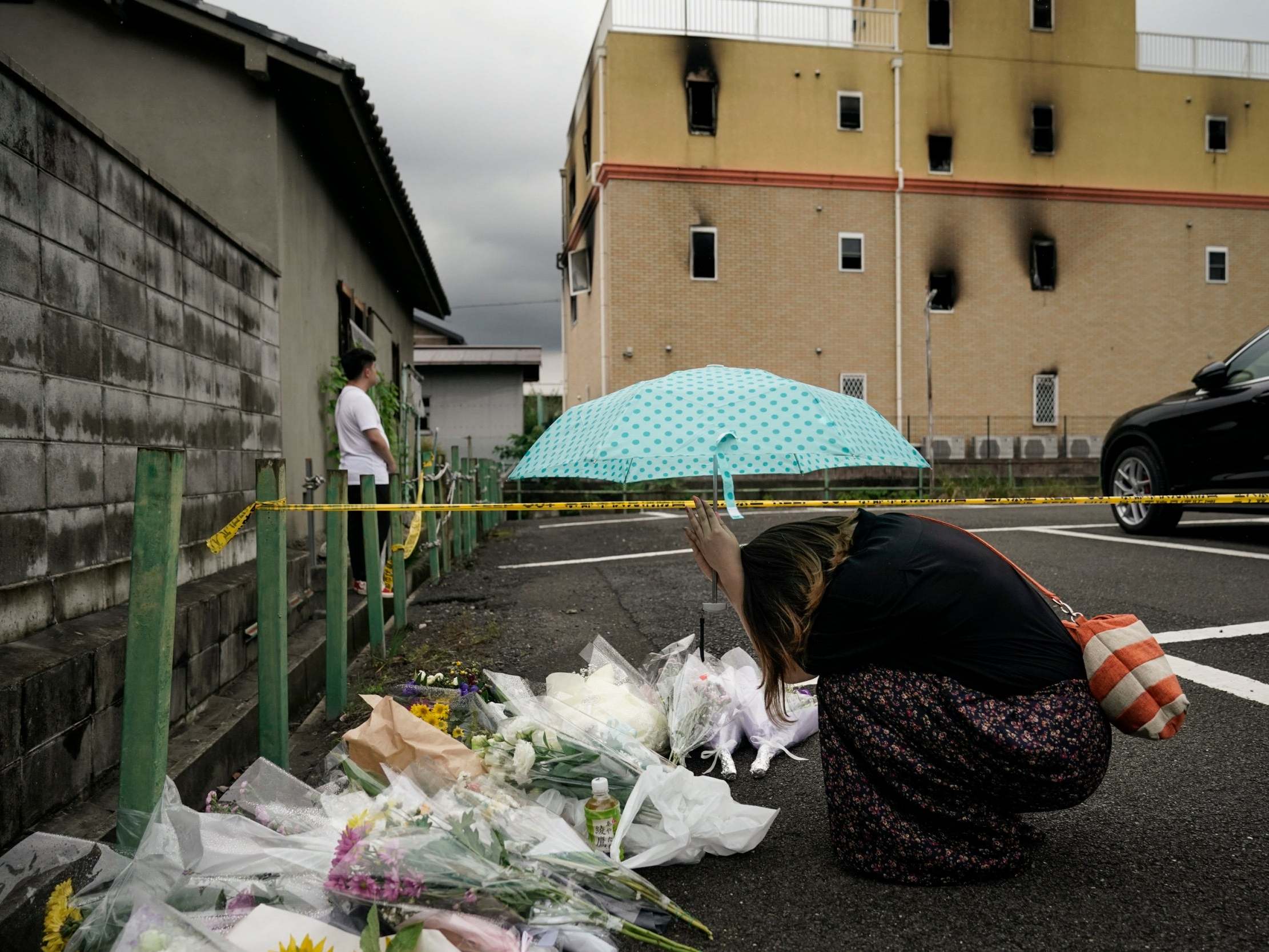 A woman prays at a makeshift memorial for victims of a suspected arson attack at the Kyoto Animation Company studio building, in Kyoto, Japan, 19 July 2019