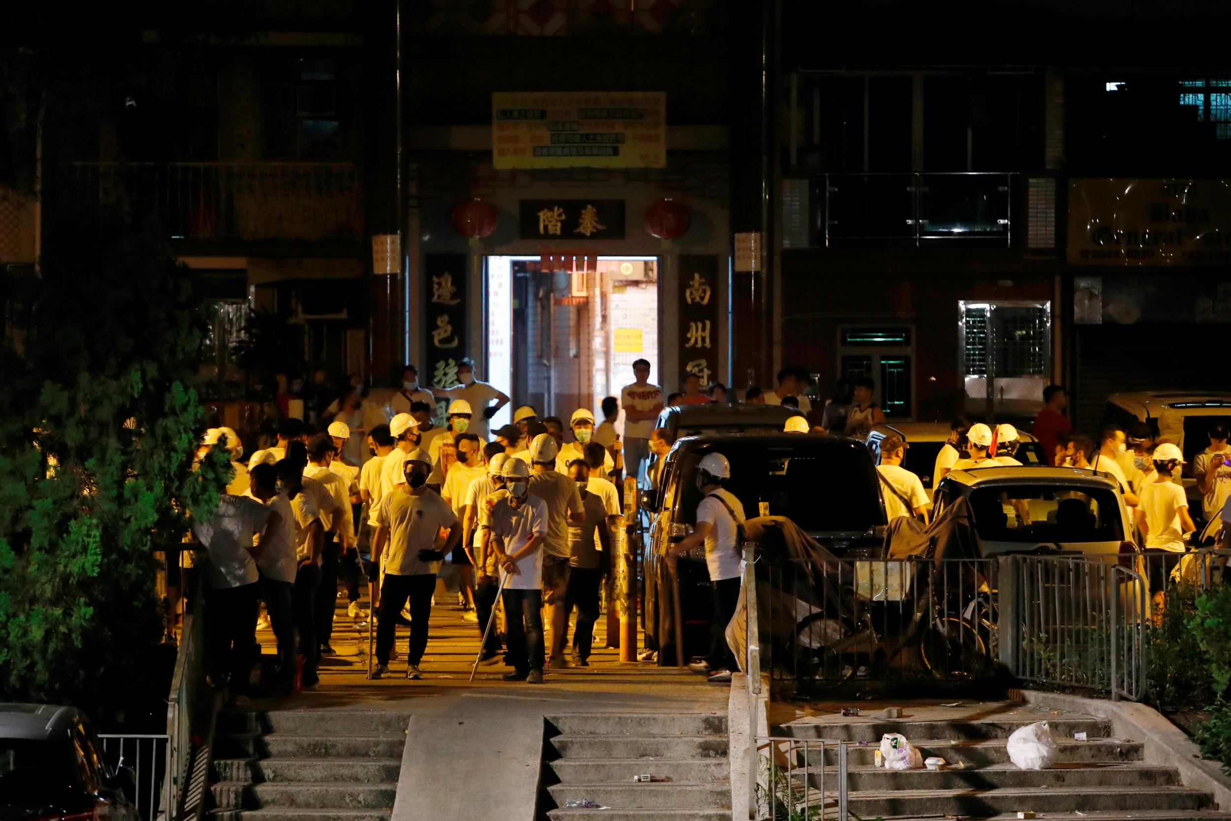 Men in white T-shirts with poles are seen in Yuen Long after attacking anti-extradition bill demonstrators at a train station