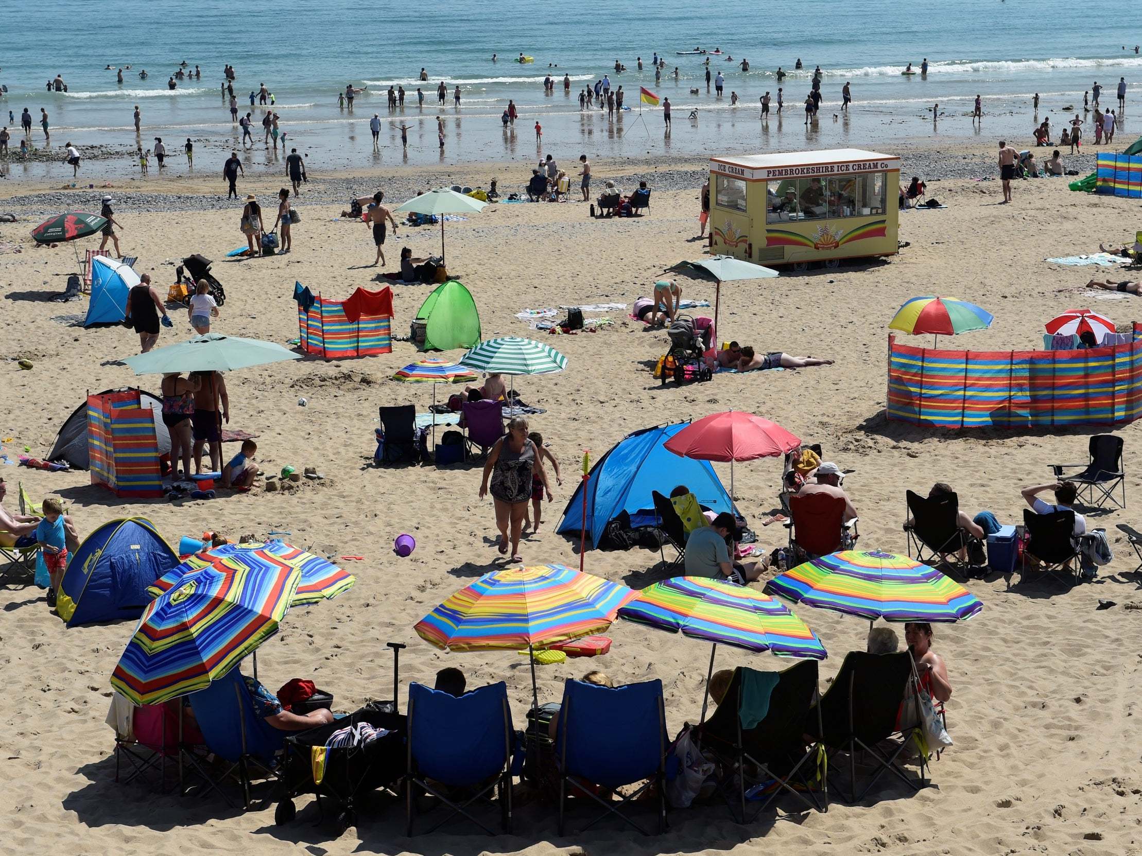 People take shade under umbrellas in Tenby, Pembrokeshire (Reuters/Rebecca Naden)