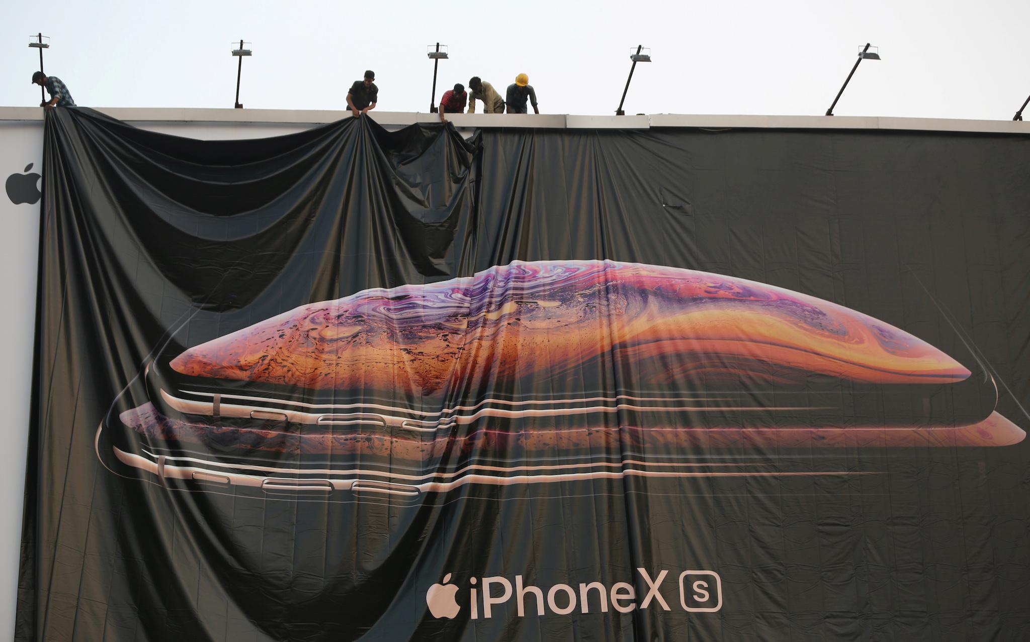 Workers adjust a hoarding of the newly launched iPhone XS in Ahmedabad, India