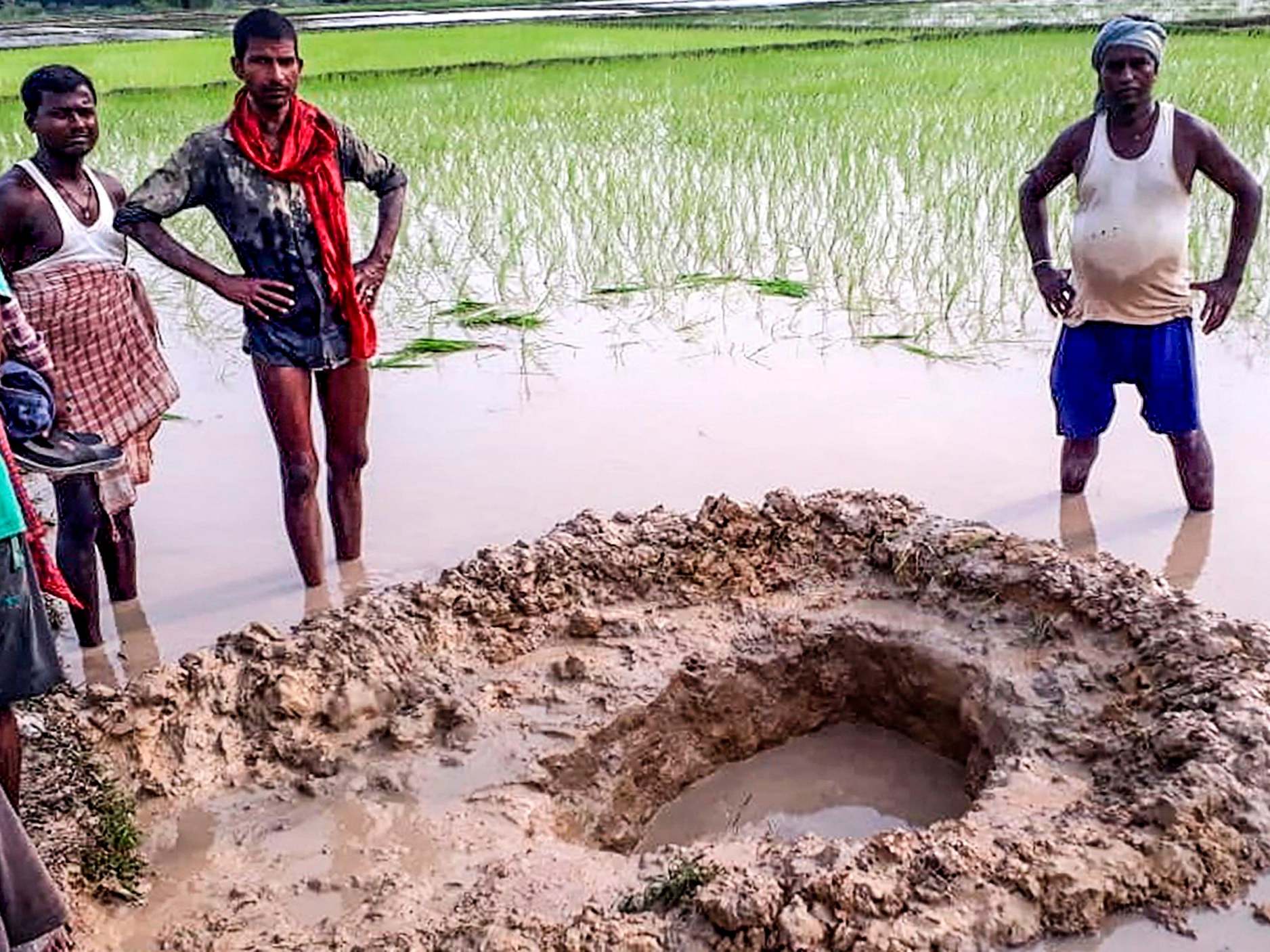 Villagers and farmers pose around the meteorite's crater