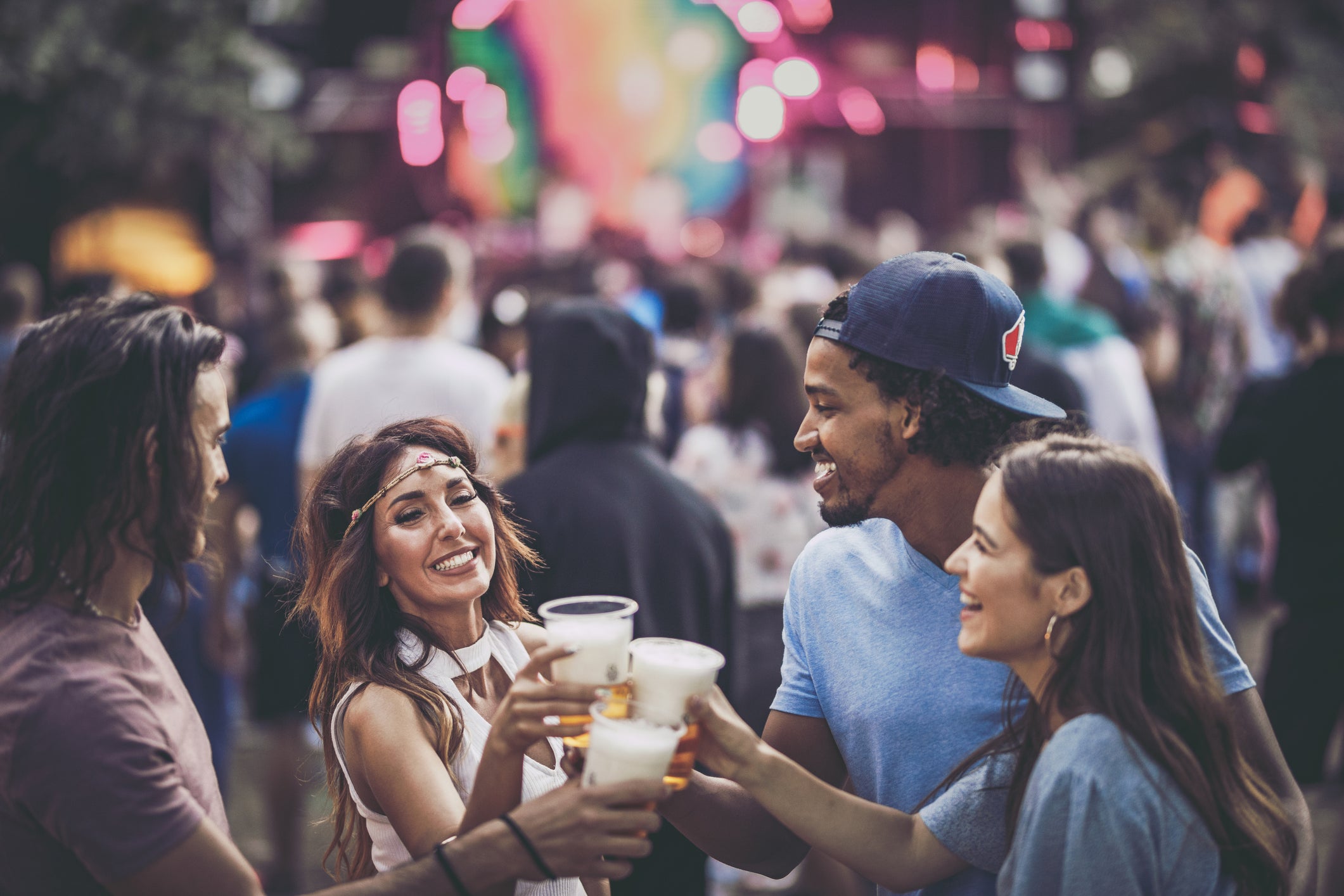 Group of happy friends toasting with beer on a music concert