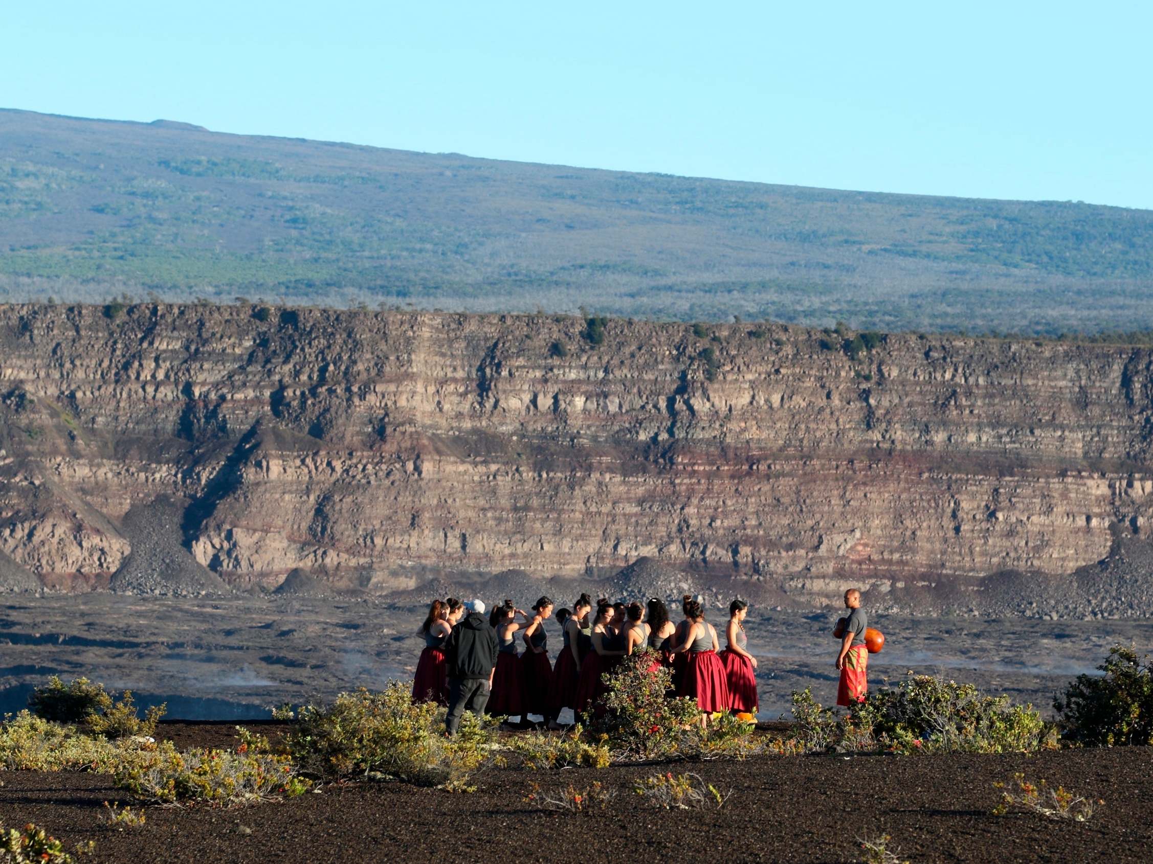 A group of Native Hawaiians stand next to the collapsed crater floor of the volcano