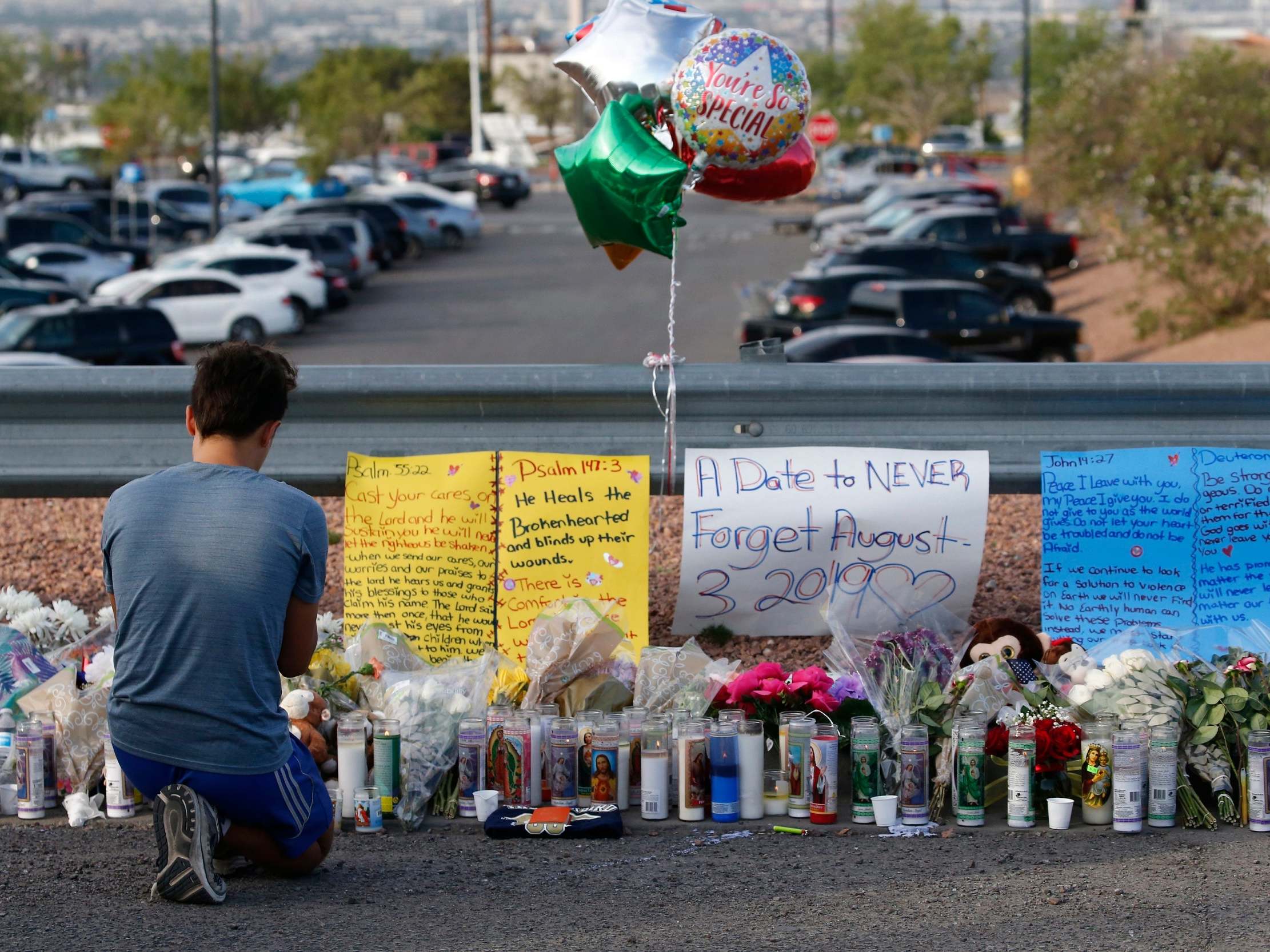 A young man prays while attending the make shift memorial along the street after the mass shooting that happened at a Walmart in El Paso