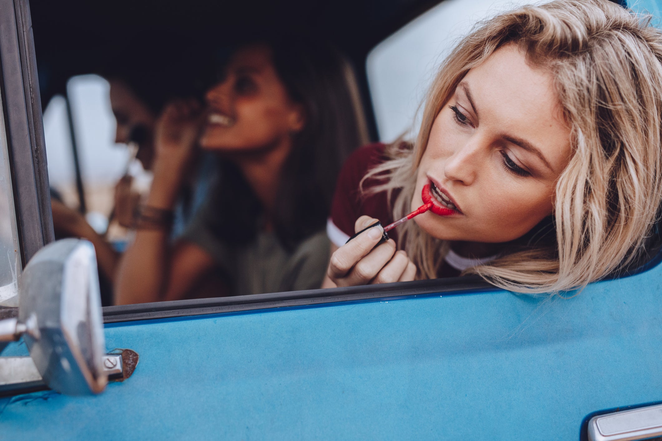 Women on road trip doing makeup in a moving car