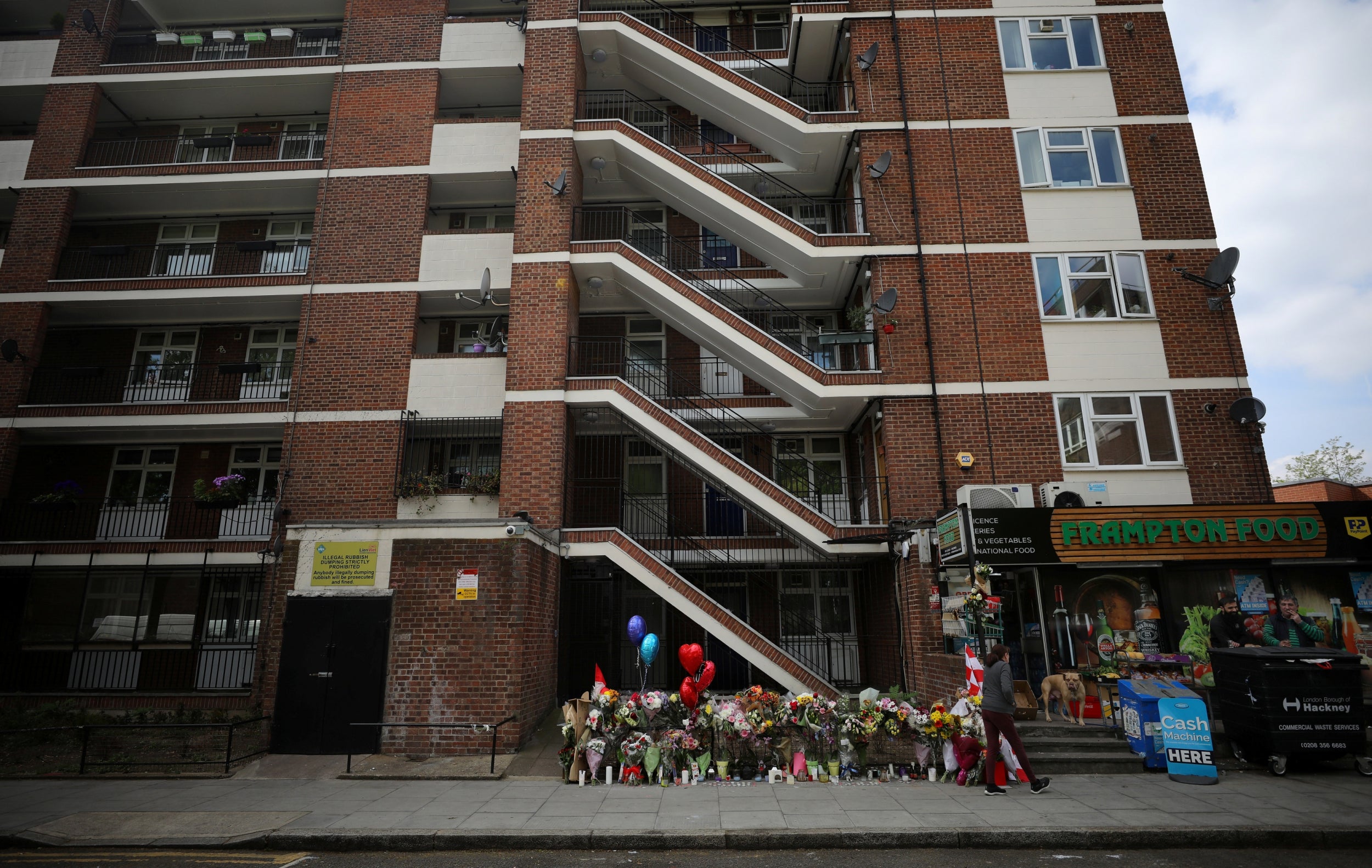 A woman walks past floral tributes near to where 29-year-old Joshua White was stabbed to death, in the Hackney area of London. Joshua White died after he was stabbed through the heart in broad daylight on April 26. Two teenagers have been charged with his murder, and police are attempting to extradite an 18-year-old from Ireland in relation to the attack.