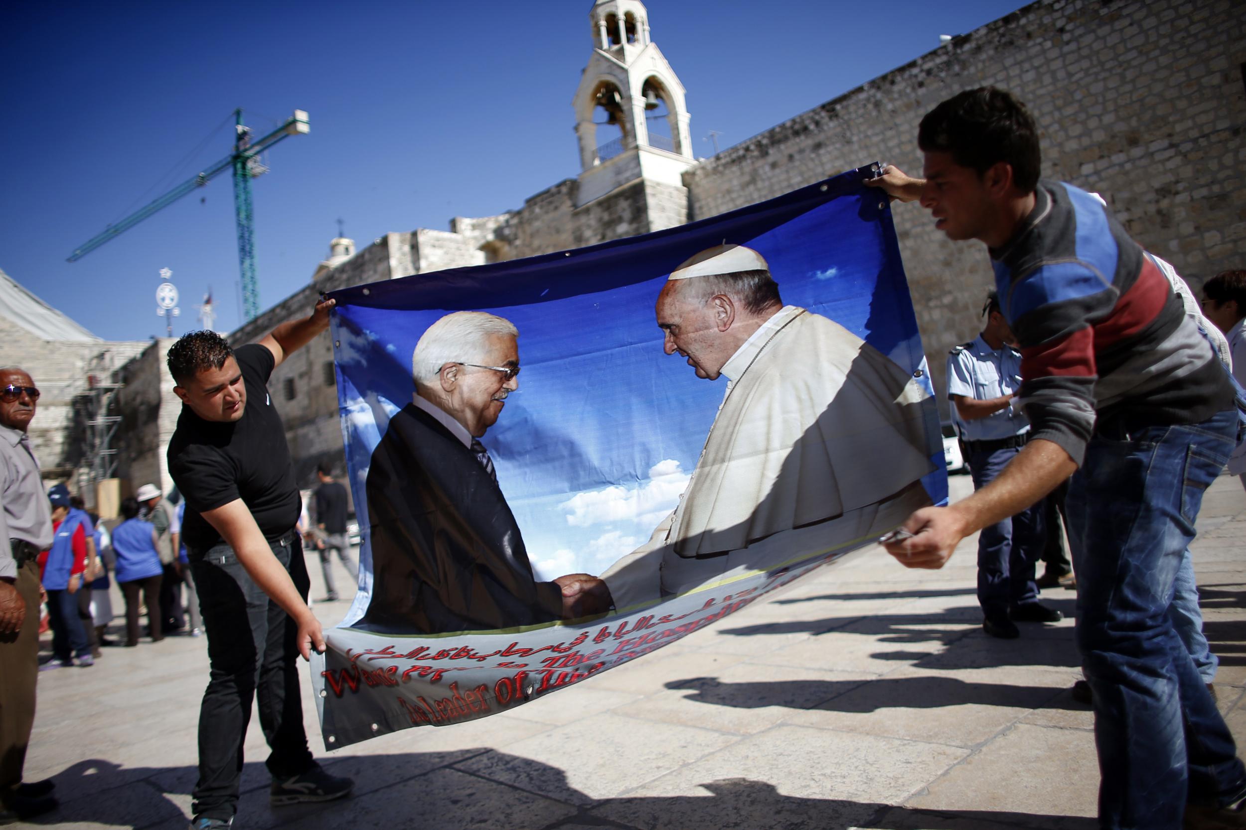 Palestinians hold a banner bearing portraits of Palestinian president Mahmoud Abbas and Pope Francis in front of the Church of Nativity in Bethlehem (AFP/Getty)