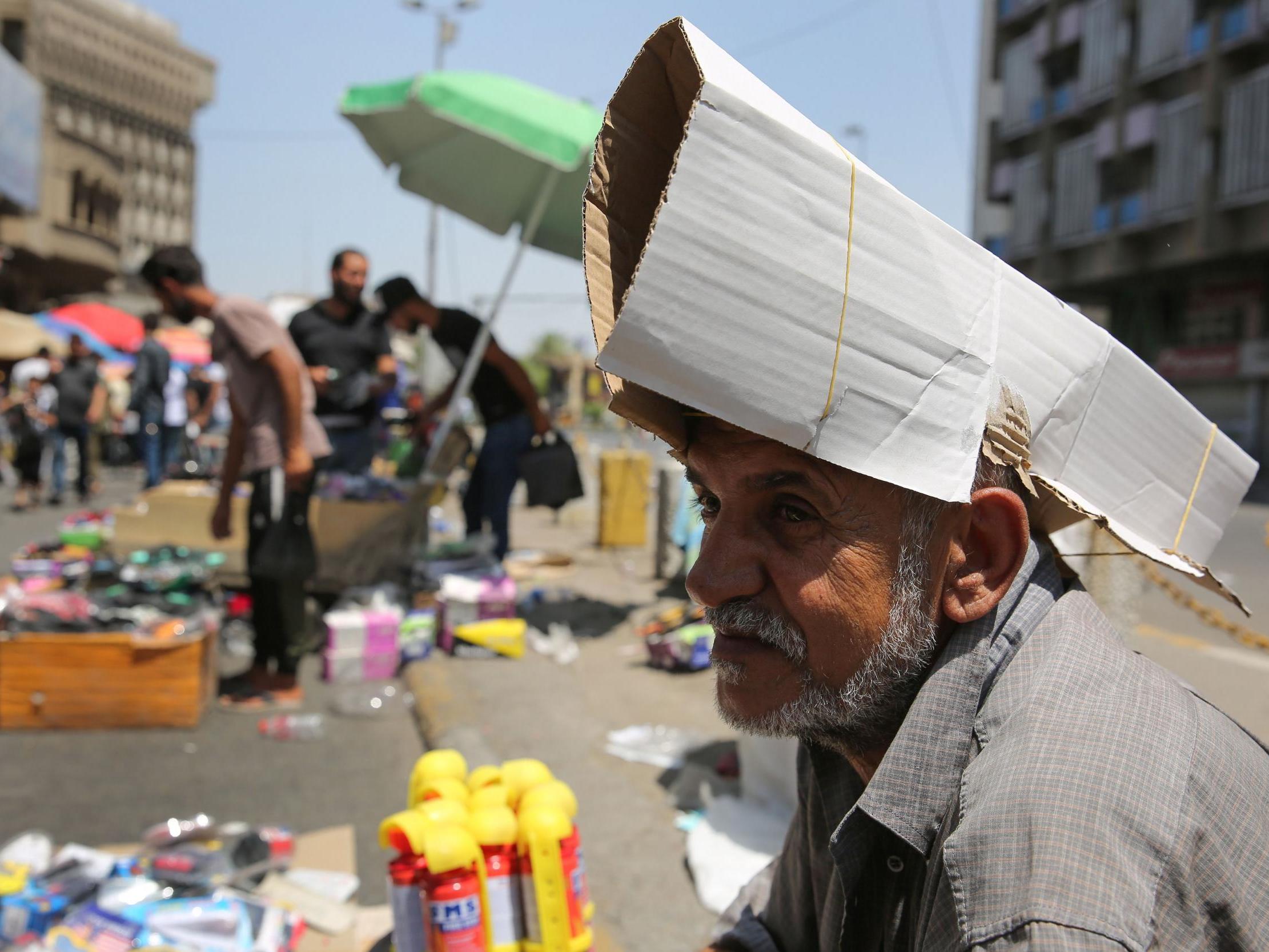 An Iraqi street vendor protects his head from the sun by using a piece of cardboard (AFP/Getty)