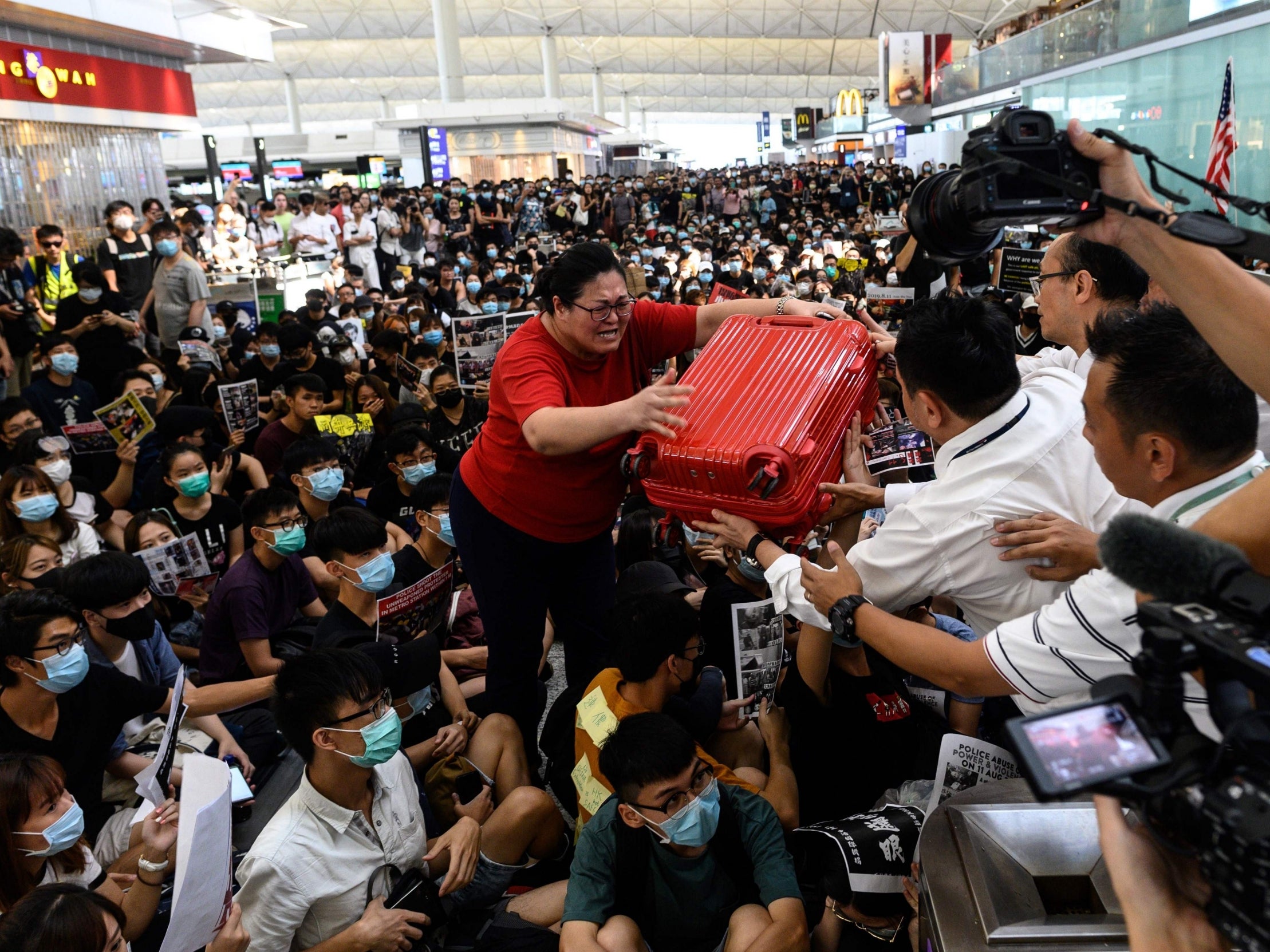 A tourist gives her luggage to security as she tries to enter the gate during a pro-democracy protest at Hong Kong international airport on Tuesday