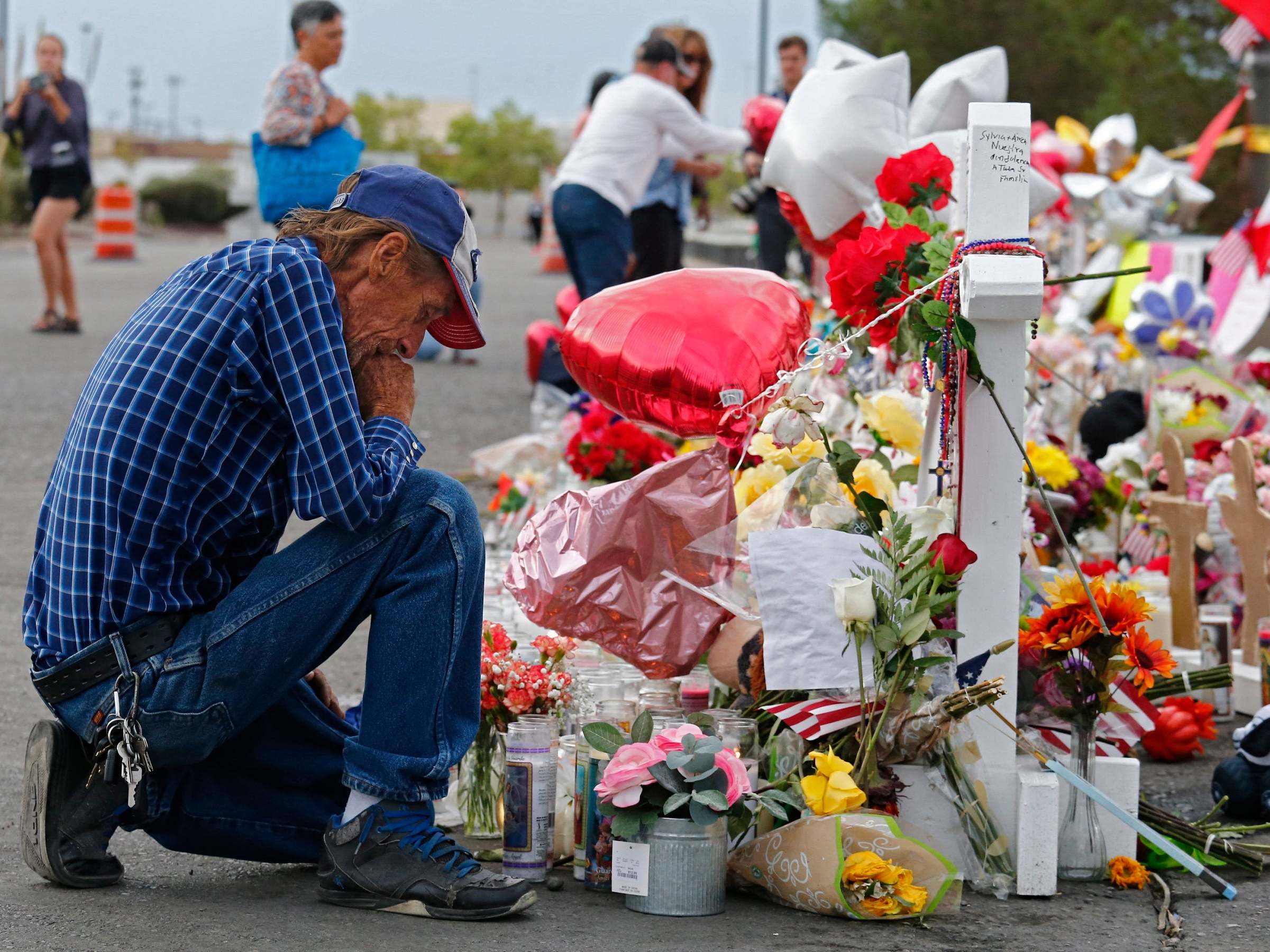 Antonio Basco kneels at a memorial for his wife Margie Reckard and other victims of the El Paso shooting