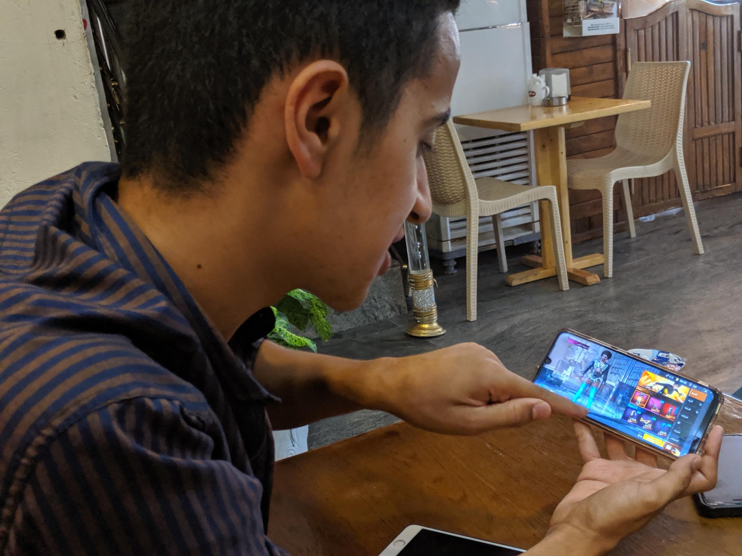 Mustafa Majid, 18, plays PUBG on his phone at a coffee shop in the Iraqi capital