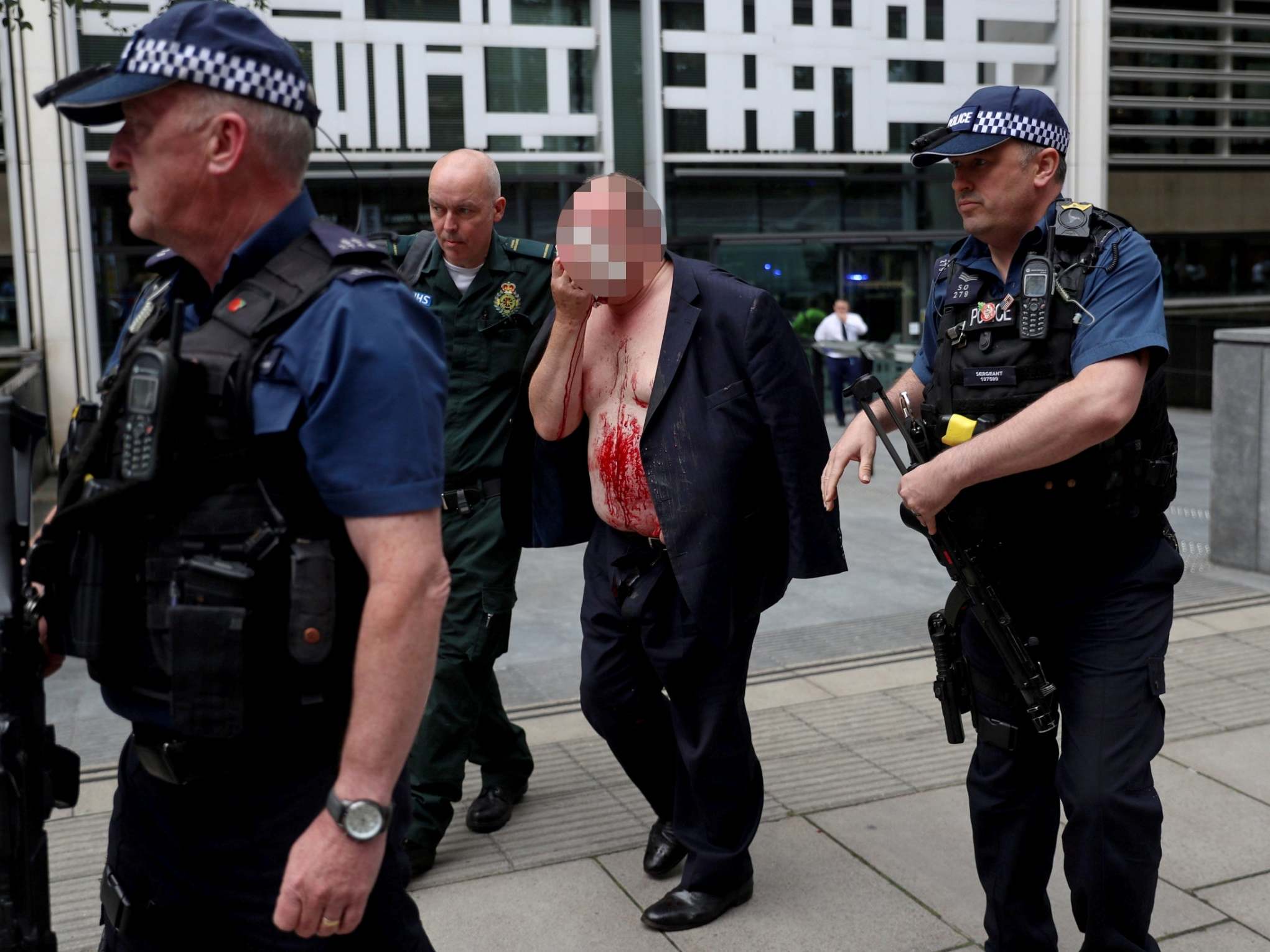 An injured man is helped by a medic and police officers outside the Home Office in London on 15 August (REUTERS/Simon Dawson)