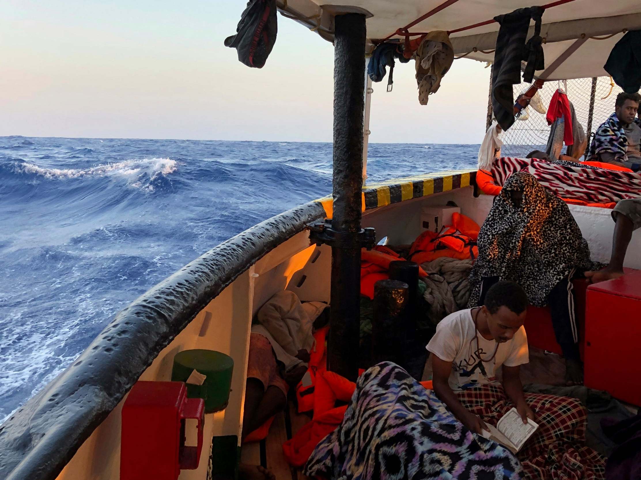 A migrant reads verses of the Quran aboard the Open Arms Spanish humanitarian boat as it arrives near the Lampedusa coast in the Mediterranean Sea