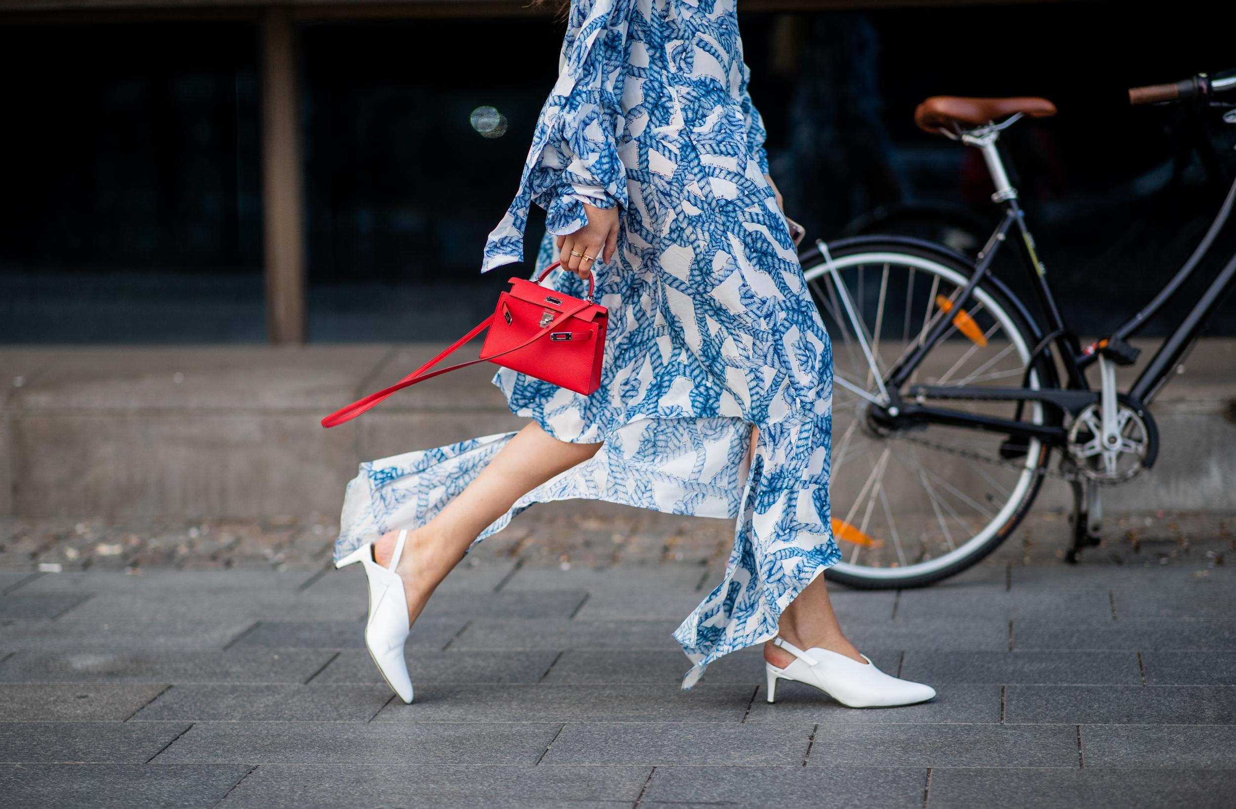 Filippa Haegg wearing blue white dress, red mini Hermes bag, white shoes is seen during Stockholm Runway SS19 on August 28, 2018 in Stockholm, Sweden.