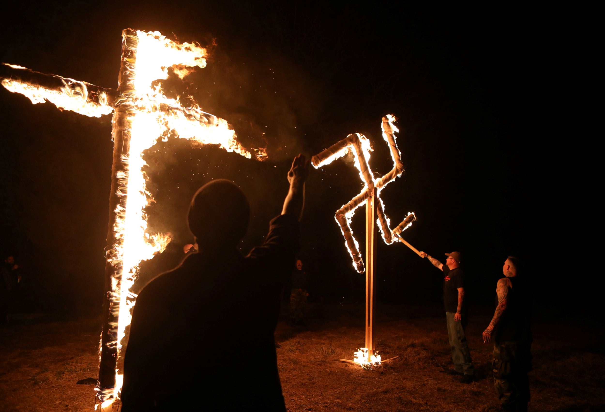 Members of the ShieldWall Network, a white nationalist group, burn a swastika and cross during a party outside Atkins, Arkansas, U.S on March 9, 2019