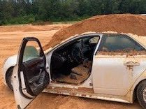 The man used a tractor to pile dirt over the borrowed Cadillac