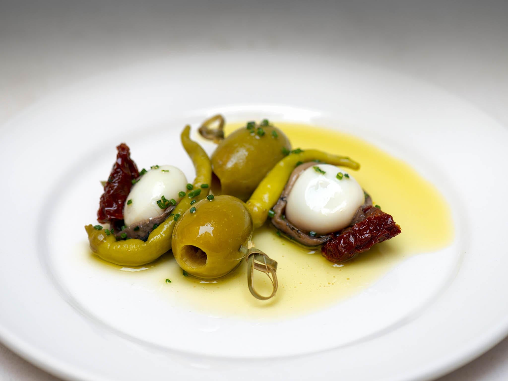 The banderillas of olive and anchovy gleam under the lights hanging above the plates