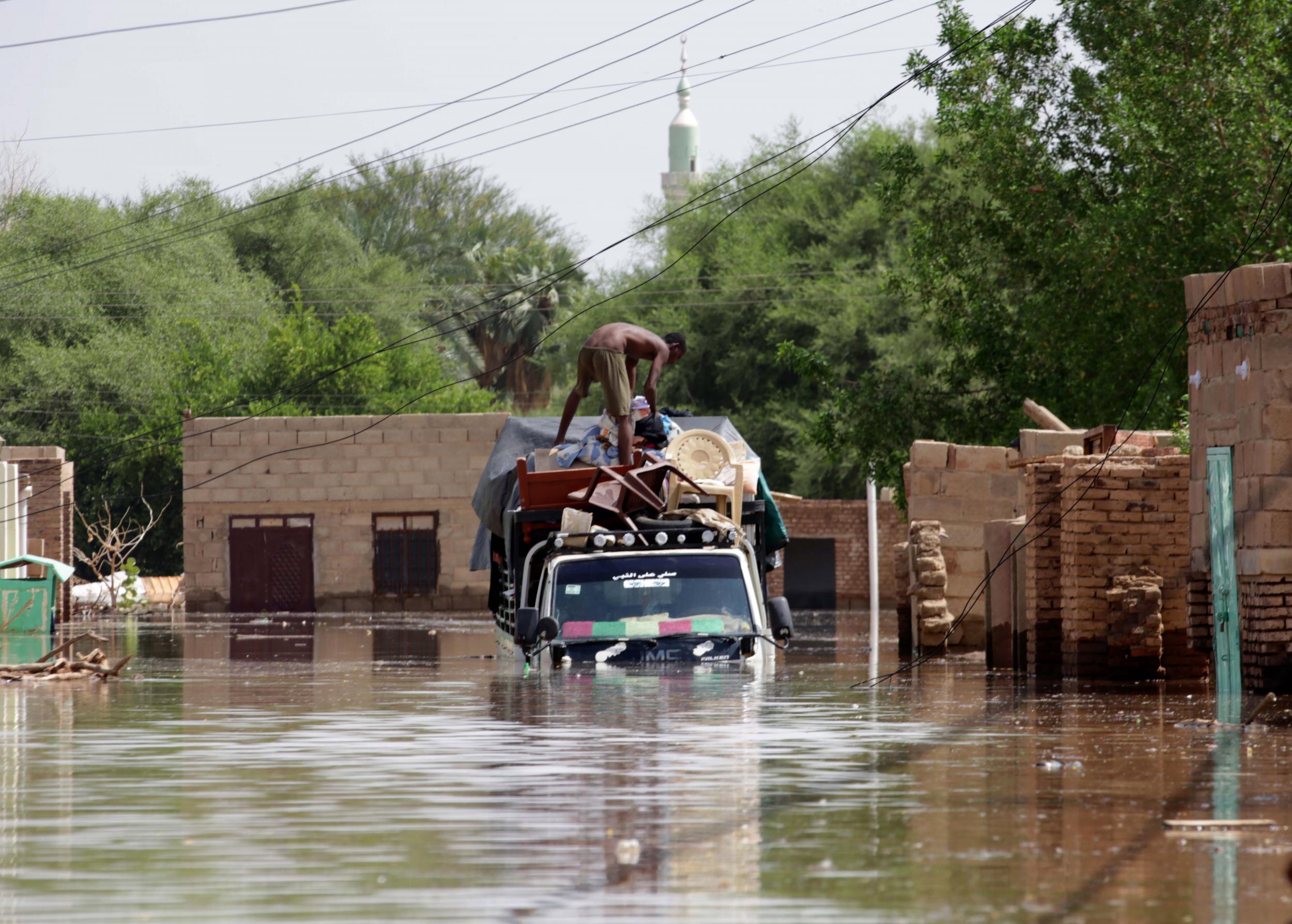 Sudanese load items they salvaged from their village onto trucks following heaving floods in Wad Ramli, some 45 km north of Khartoum