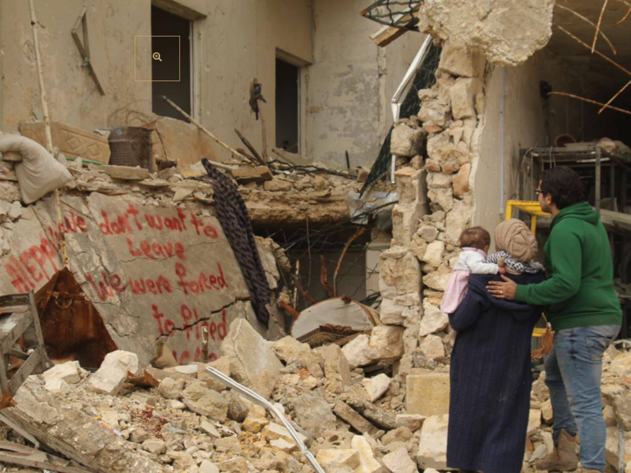 Waad, Hamza and baby Sama look at graffiti they painted on a bombed-out building in east Aleppo