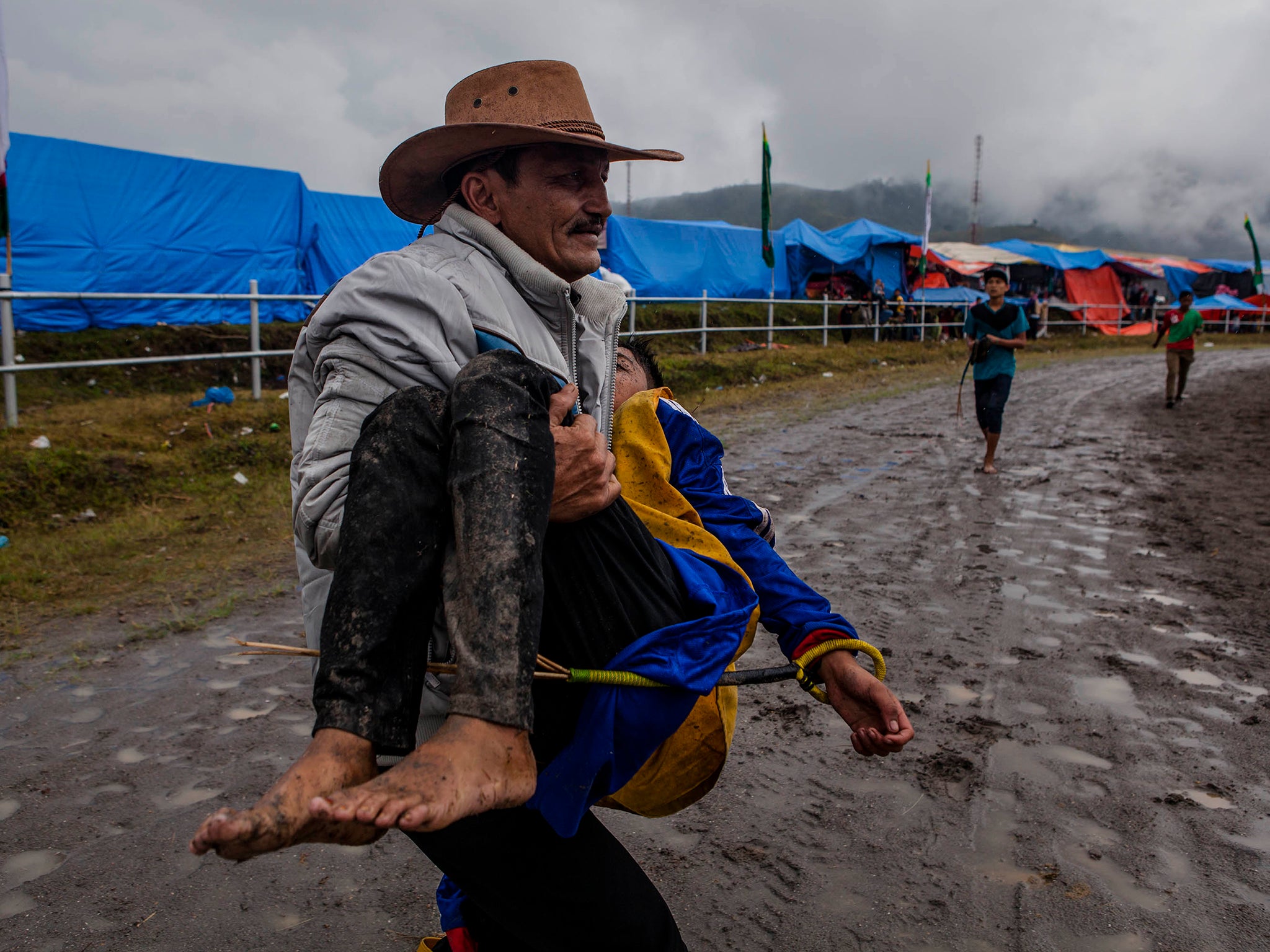 A man carries an injured child jockey who fell from his horse during the Takengon traditional horse races on Sumatra