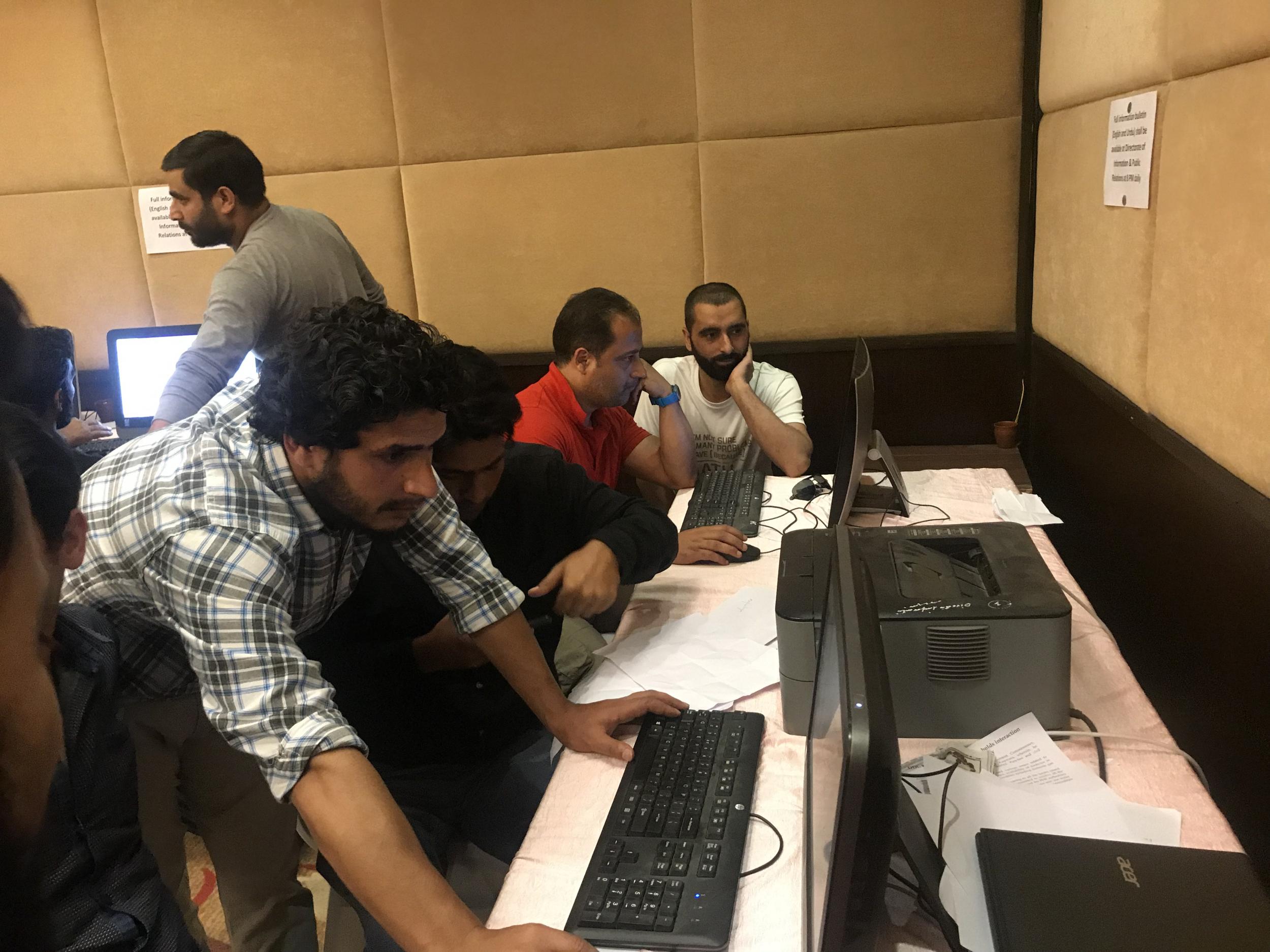 Journalists crowd around to use a small number of internet-enabled government computers in Srinagar