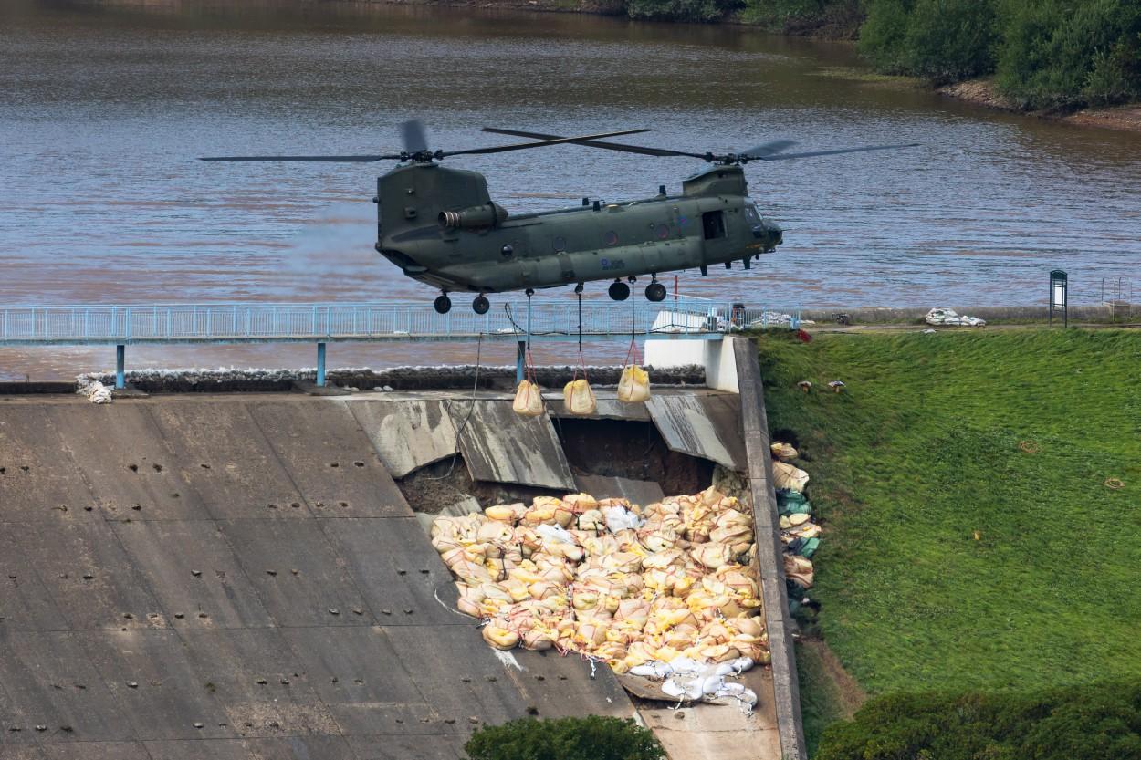 An RAF Chinook helicopter flies in sandbags to help repair the dam at Toddbrook Reservoir