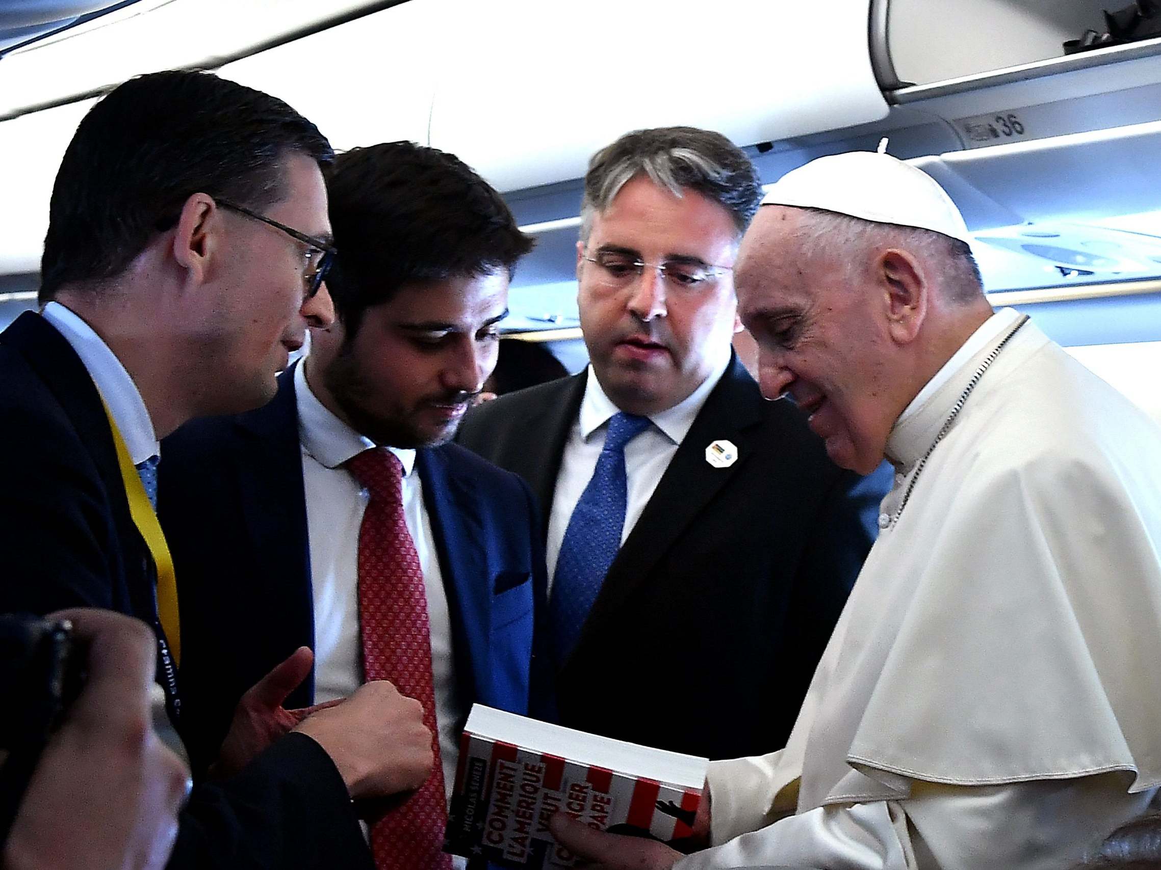 Pope Francis holds the book 'How America Wanted to Change the Pope' on board of the plane on the way to Mozambique