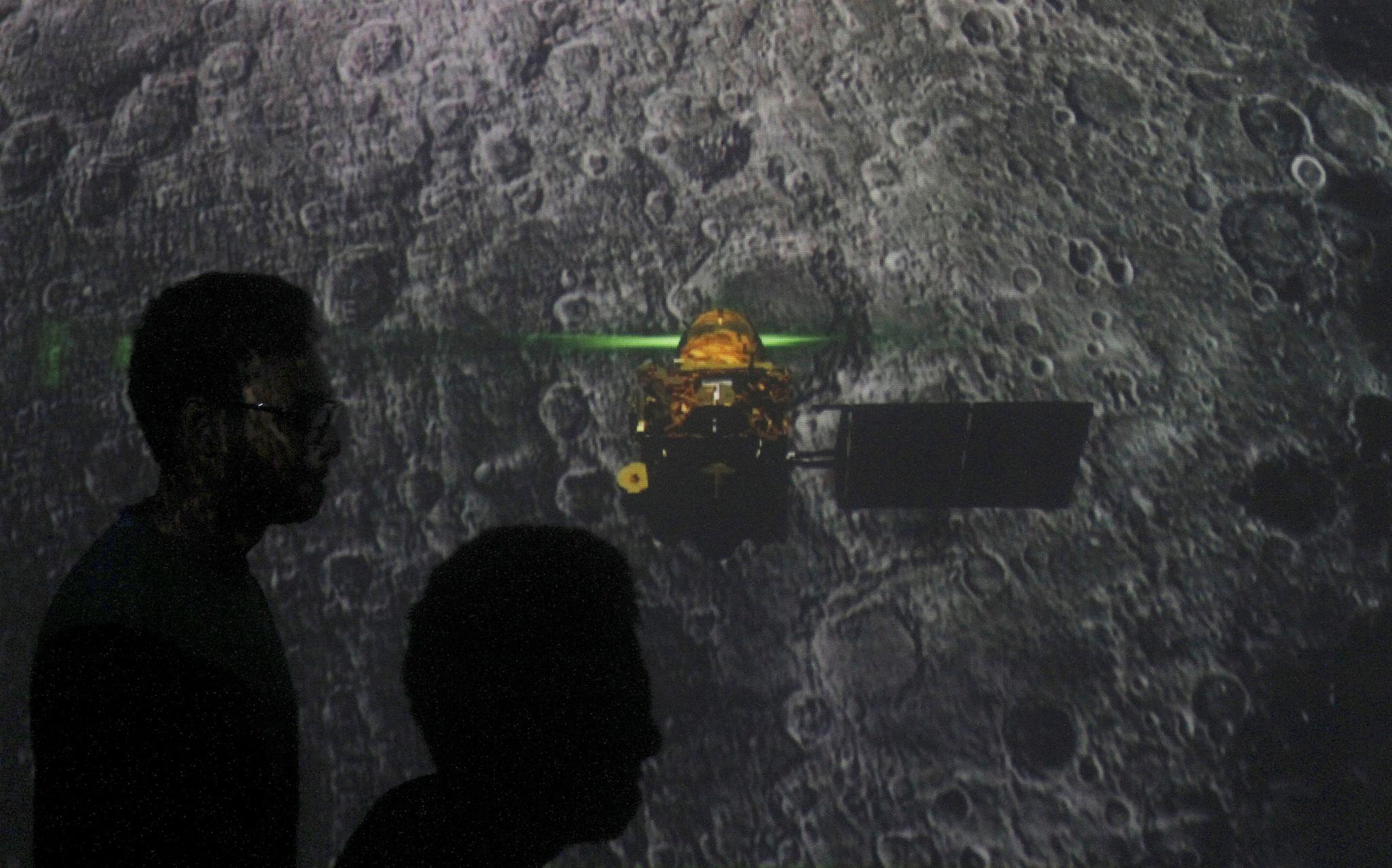 Student walk past a screen during a live streaming of Chandrayaan-2 landing at an educational institute in Mumbai, India